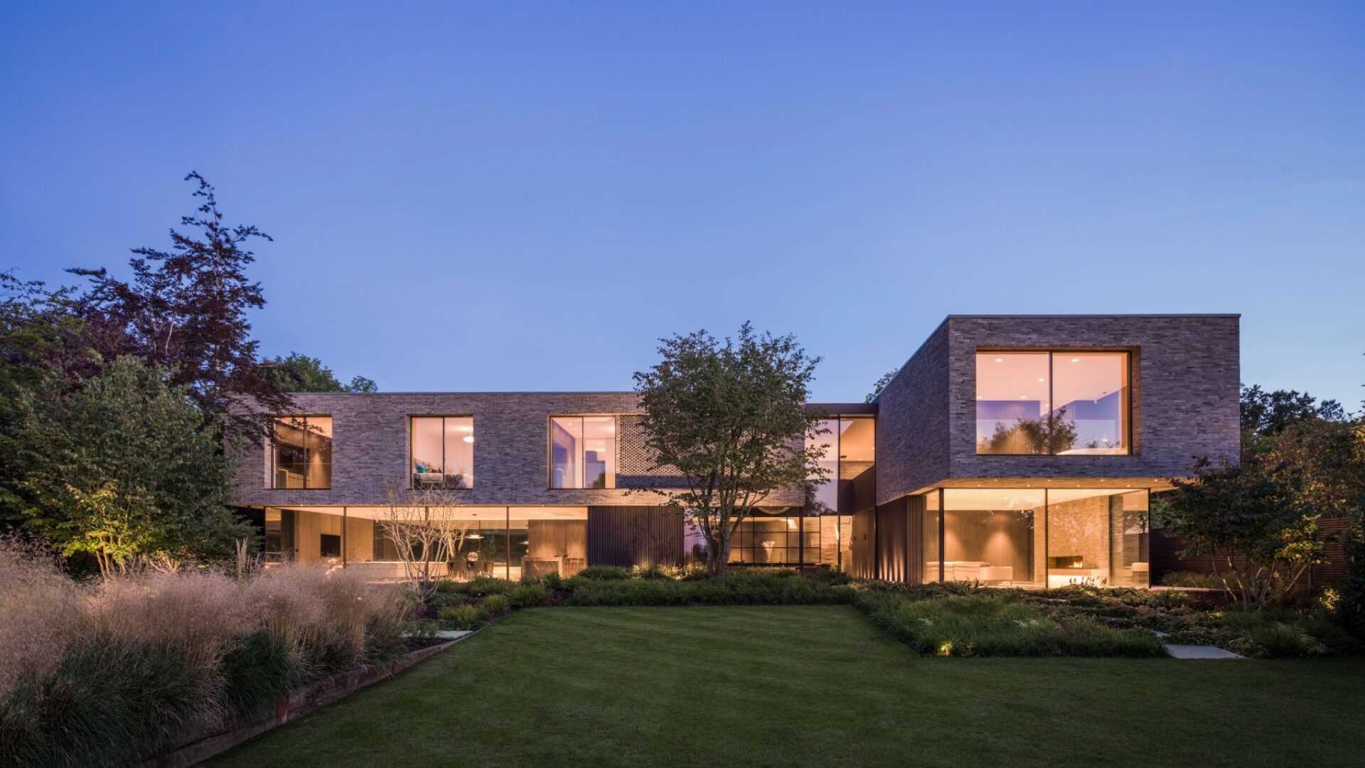 A modern house built with a waterstruck brick exterior and large windows.