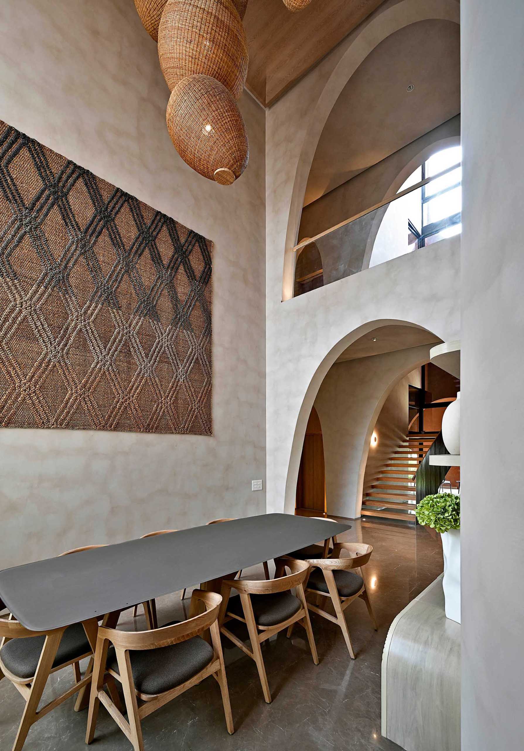 In this modern dining room, the double height ceiling provides a glimpse of the arches on both levels of the home.