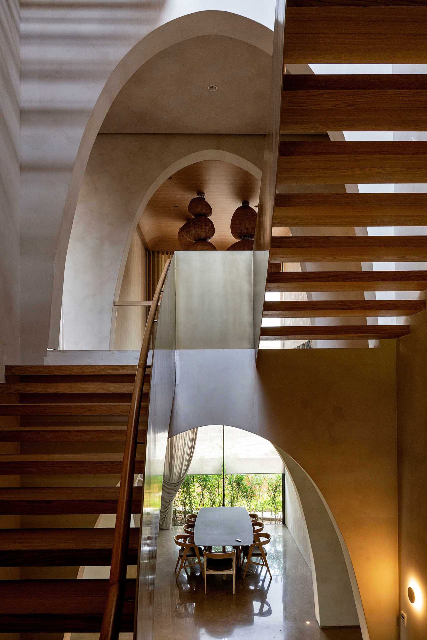 This modern wood and metal staircase connects the various levels of the home, with each level being greeted by an arch.