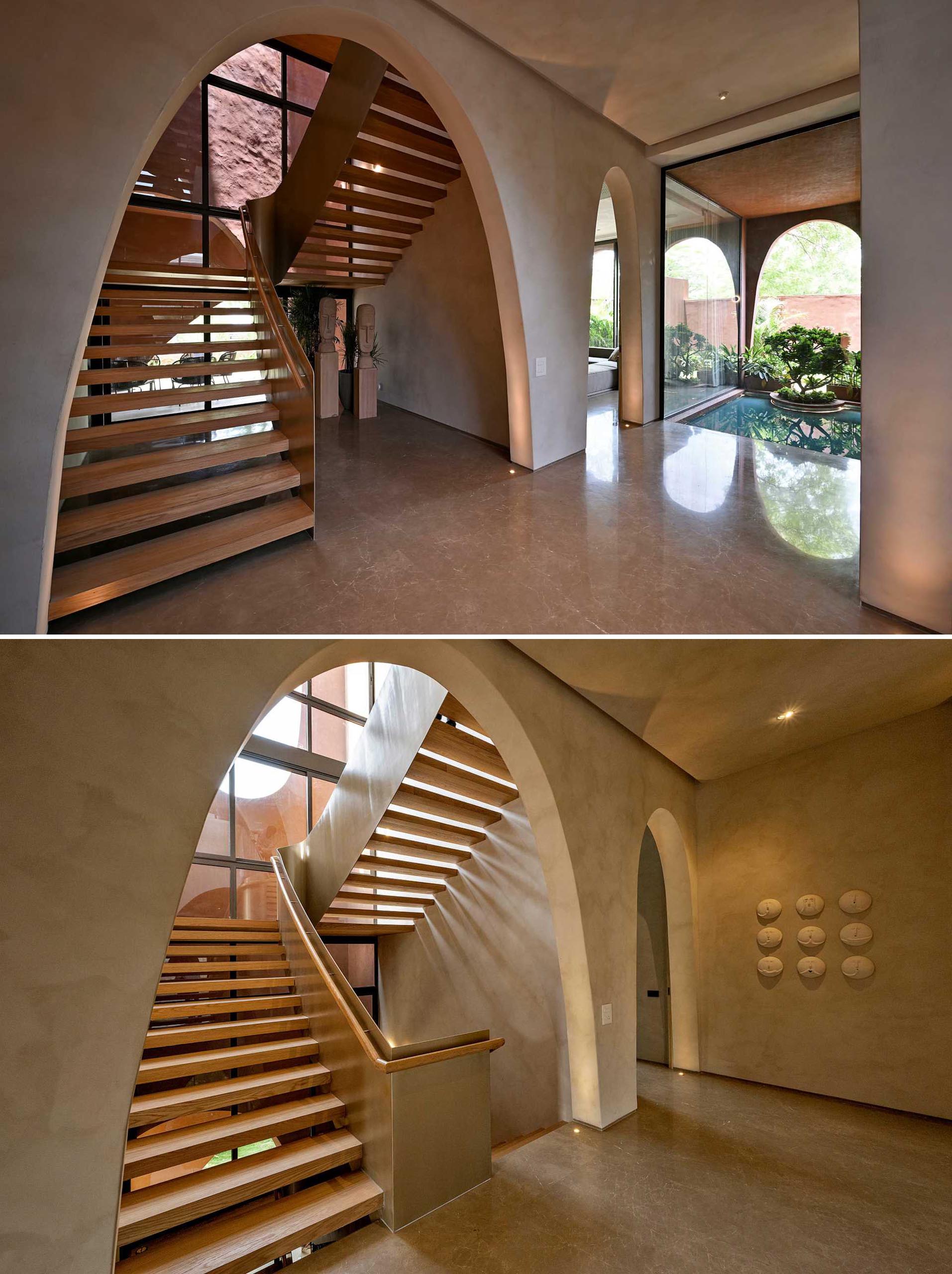 This modern wood and metal staircase connects the various levels of the home, with each level being greeted by an arch.