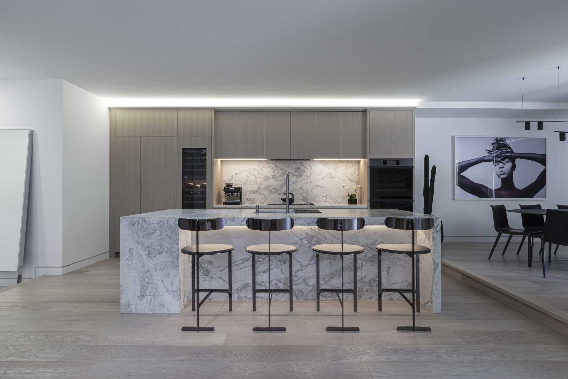 In the kitchen, a large island provides a place for seating, while the minimalist cabinets line the wall.