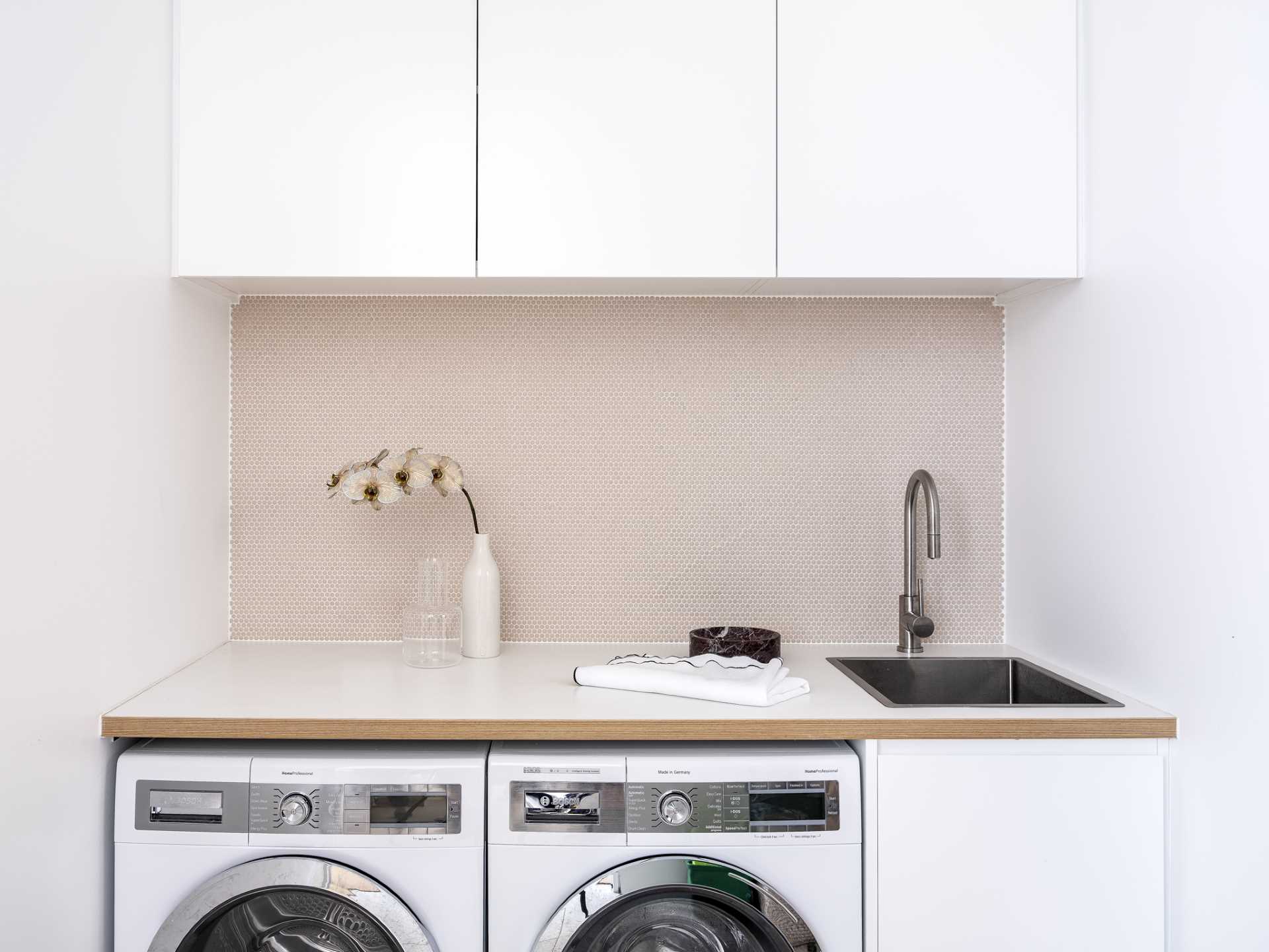 In this laundry room, a counter has been placed across the washing machine and dryer, creating a place for folding clothes, while cabinets add storage.