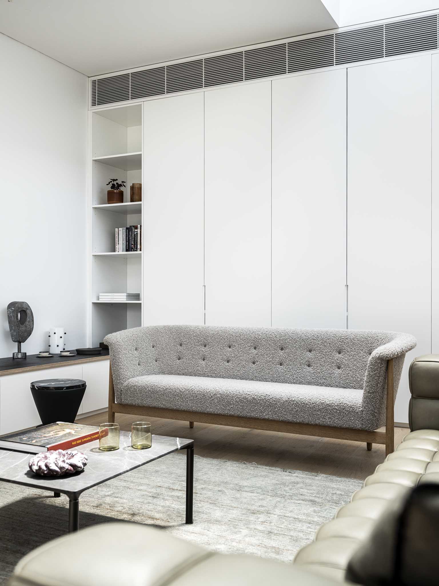 A modern living room with a wall full of storage cabinets and shelves.