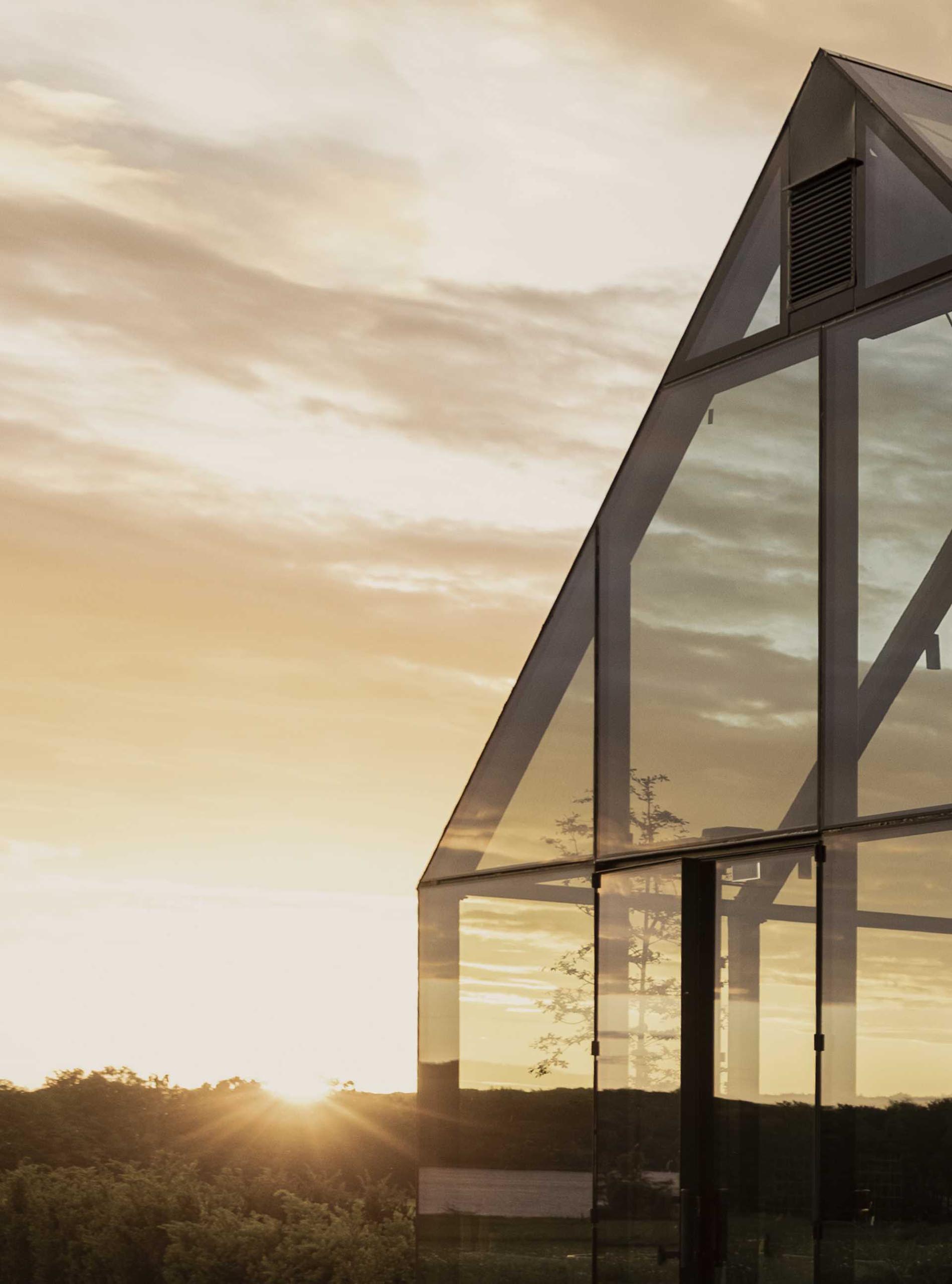 A modern restaurant within a glass-house inspired building, includes thick black steel framing.