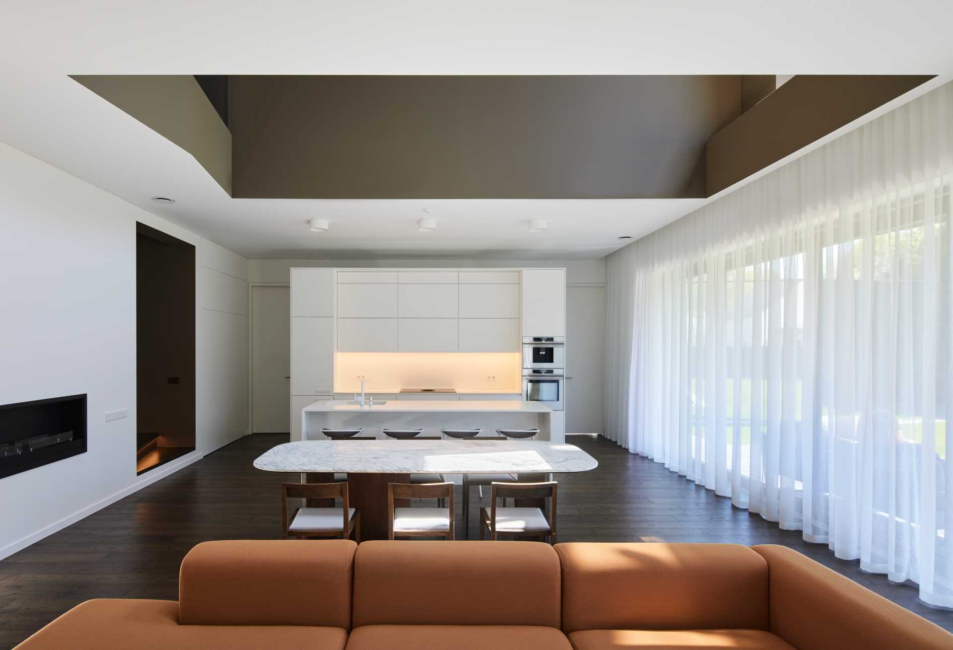 A modern home interior with an open plan living room, dining area, and white kitchen.