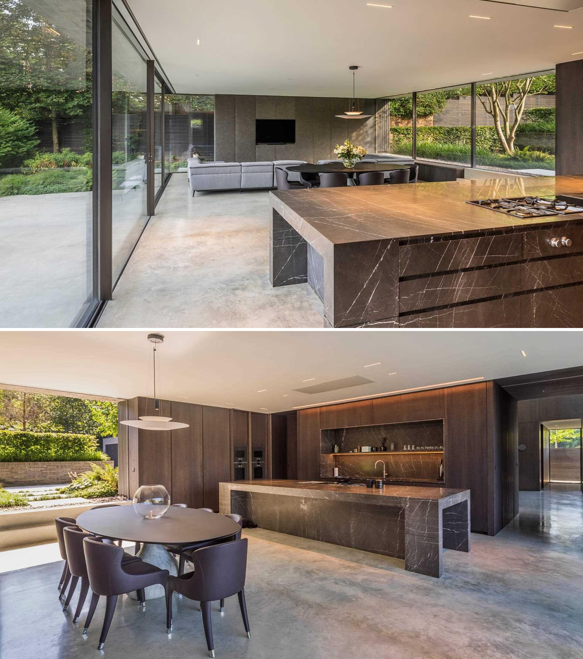 The interior of this modern home has concrete flooring, minimal furnishings, and a kitchen with a large island that looks out over both sides of the garden.