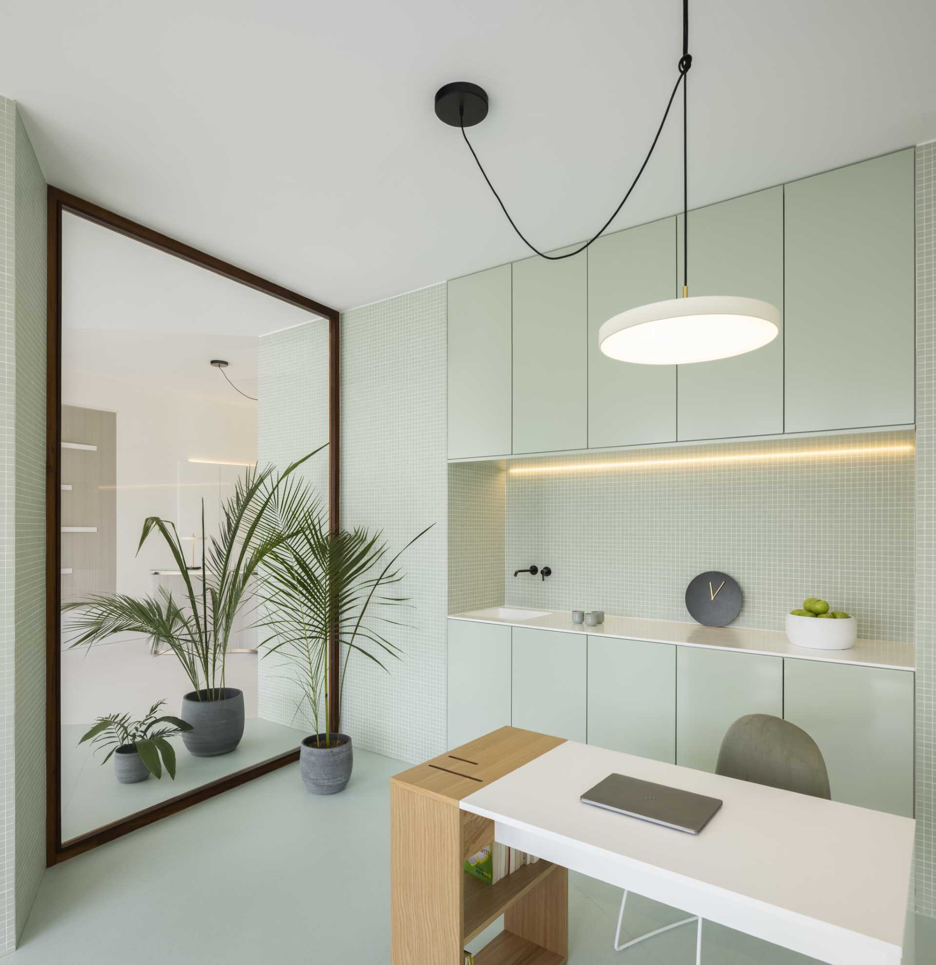 A modern health clinic office includes pastel green cabinets and tiles.