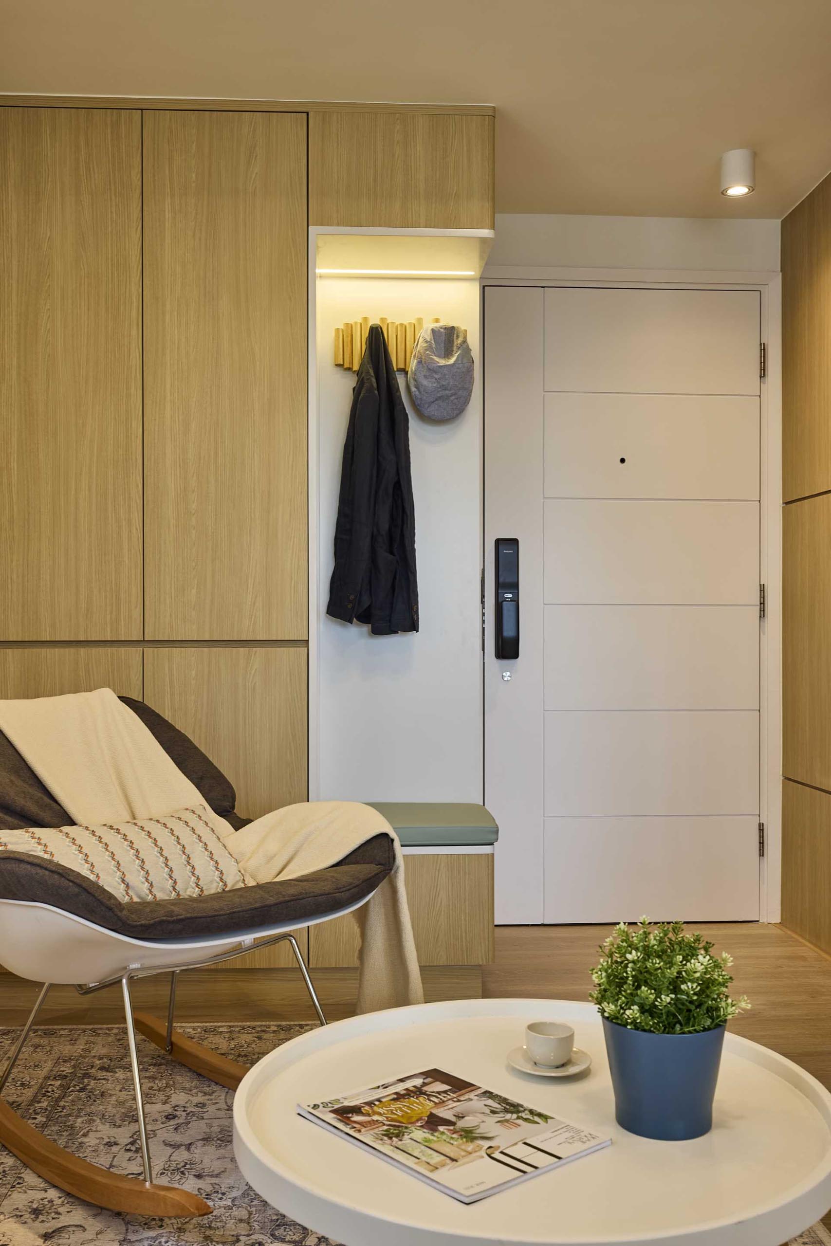 Stepping inside this small apartment, there's an entryway with storage cabinets and a bench with coat hooks above.