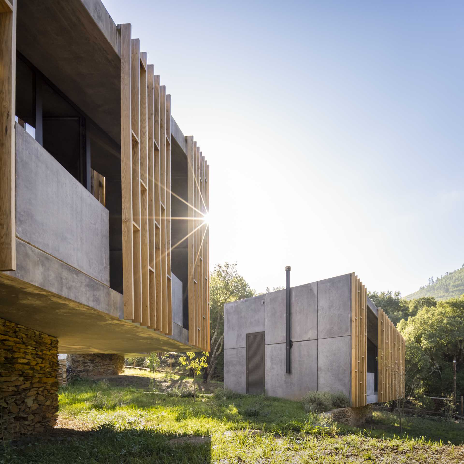 A small and modern houses that are  made from raw concrete and wood, and have pathways between them.