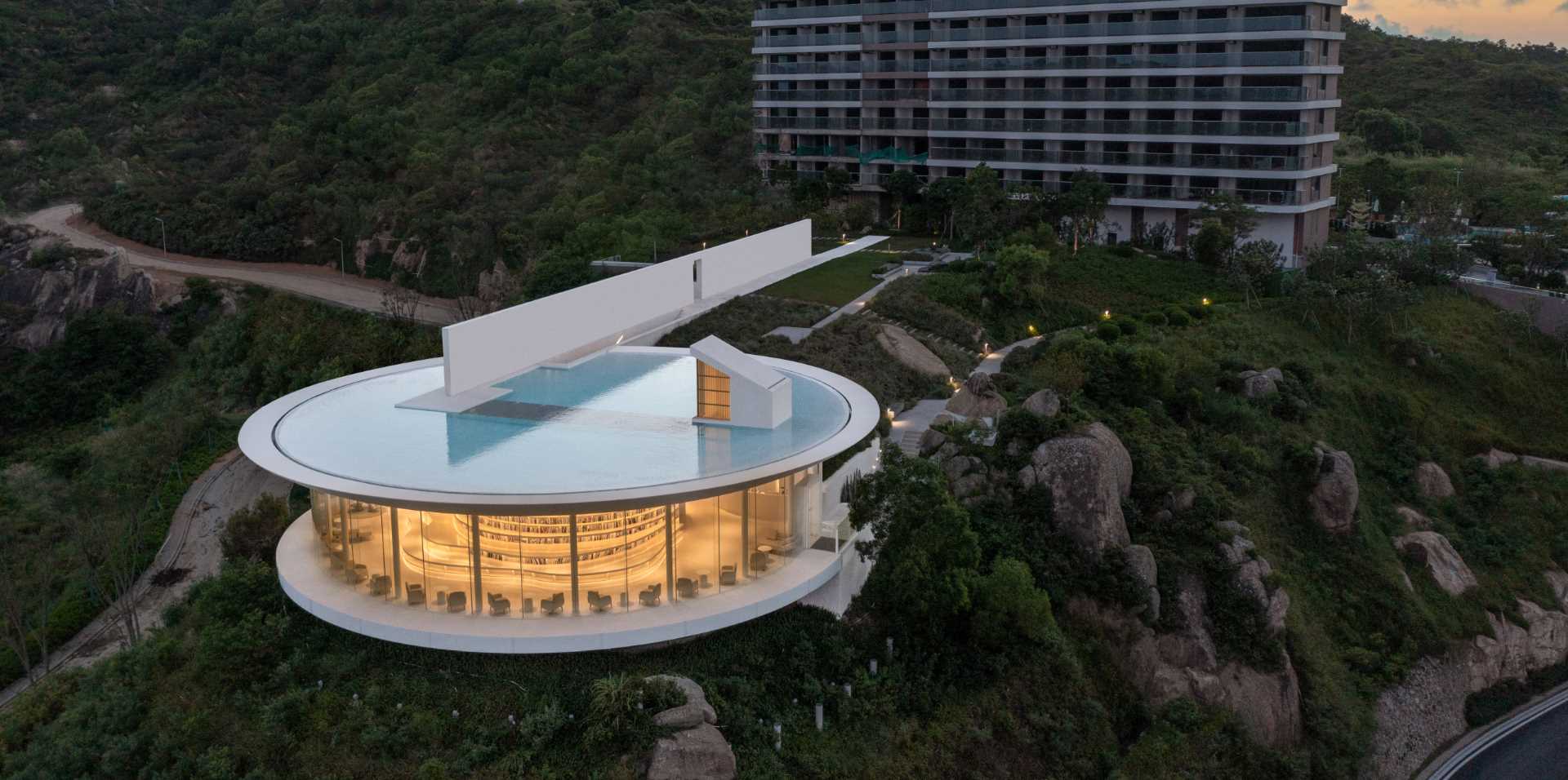 A modern round library with a shallow rooftop water feature.