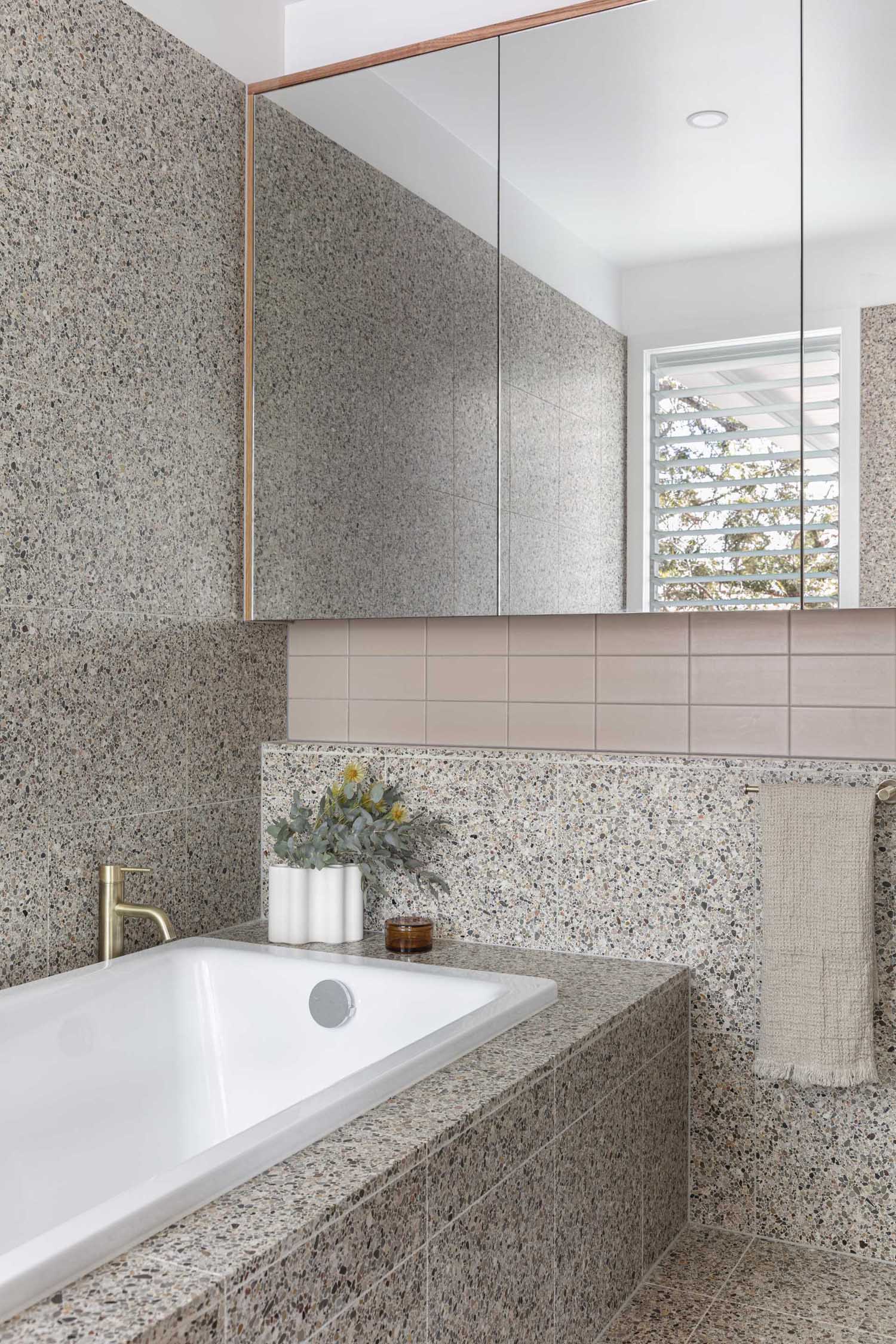 A modern bathroom with tiled walls and a built-in bathtub.