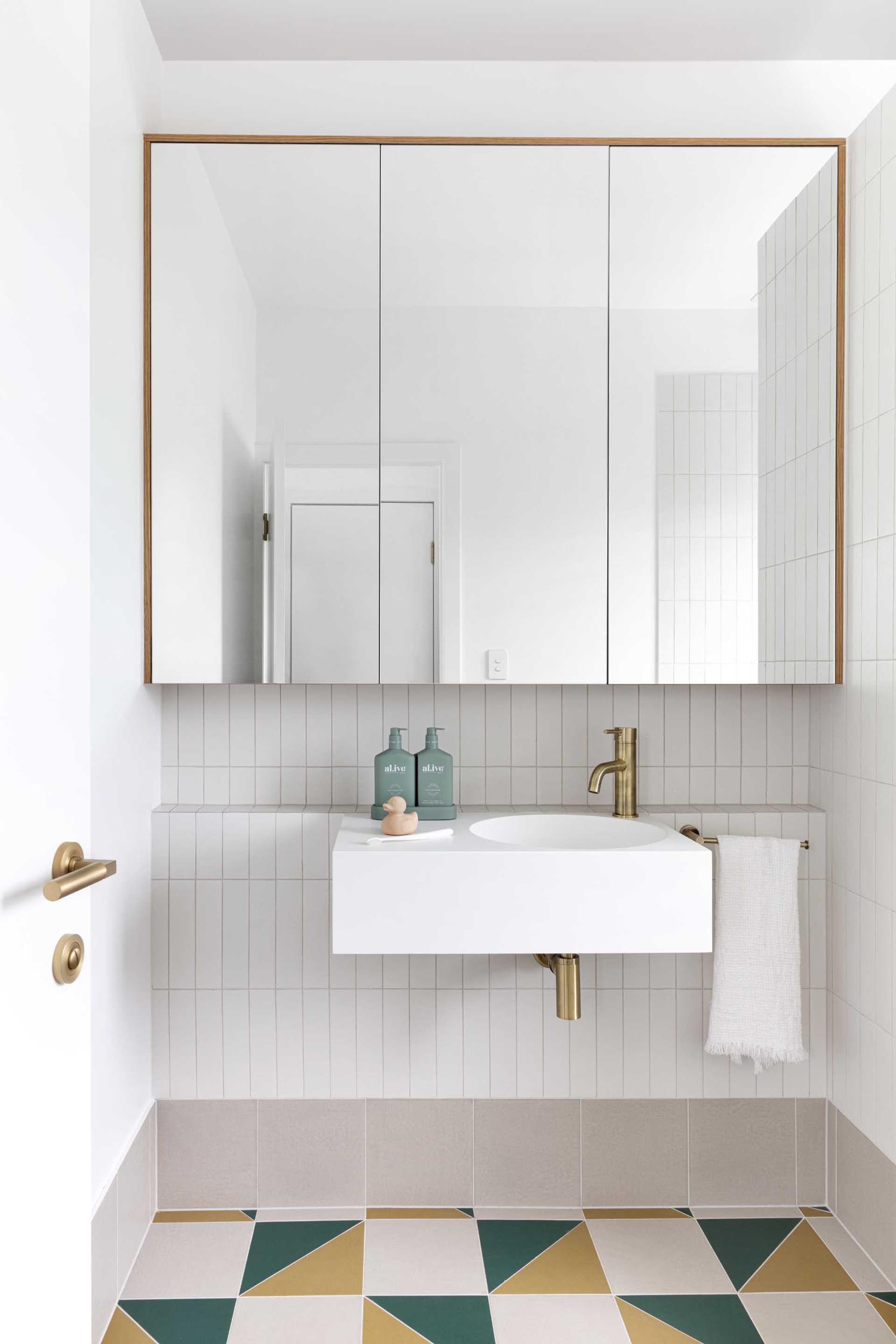 This kids bathroom has a neutral palette, however colorful floor tiles add a hint of fun.