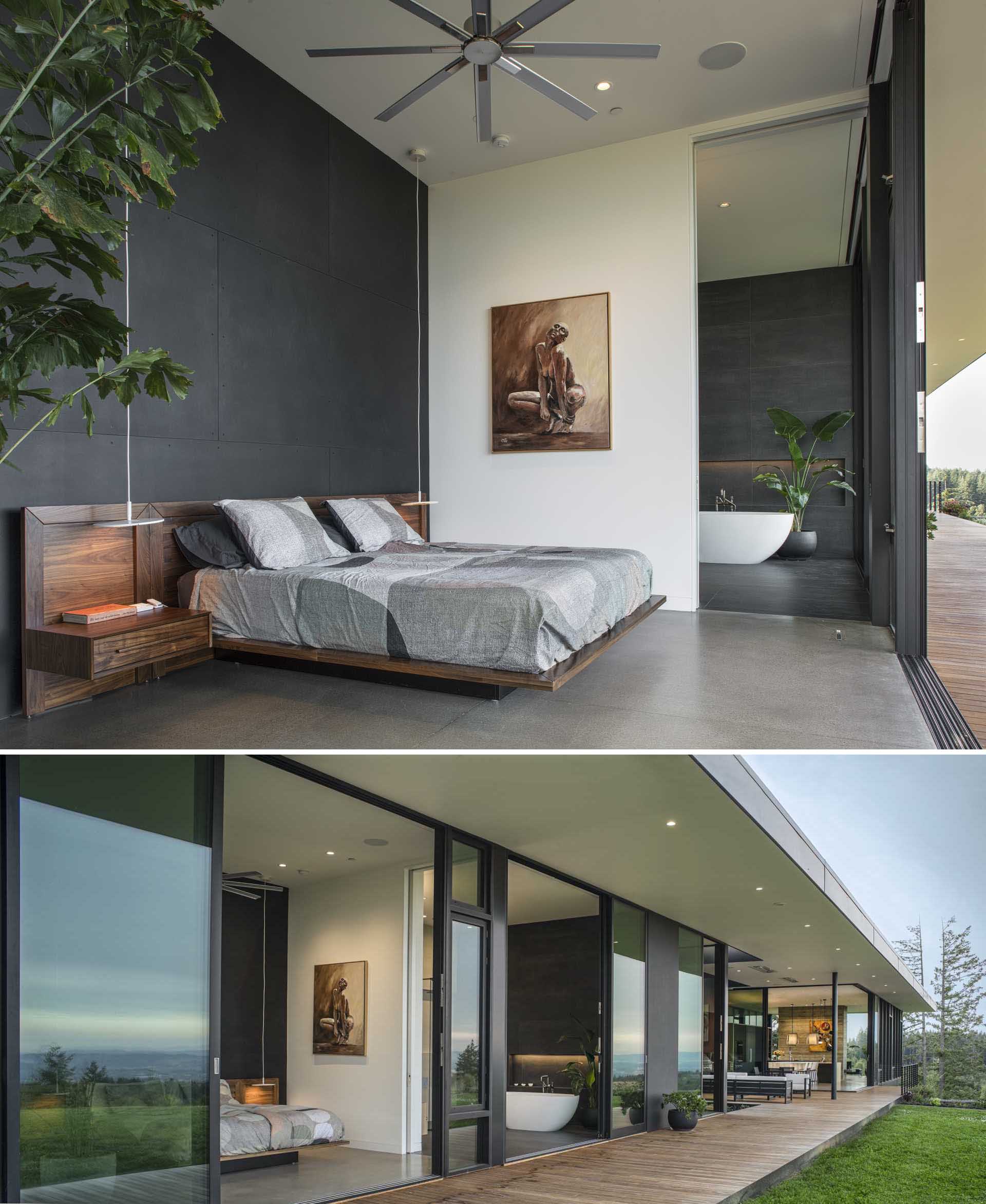 In this modern bedroom, a black accent wall creates a dramatic backdrop for the wood-framed bed, while a matching dark wall is also featured in the bathroom.