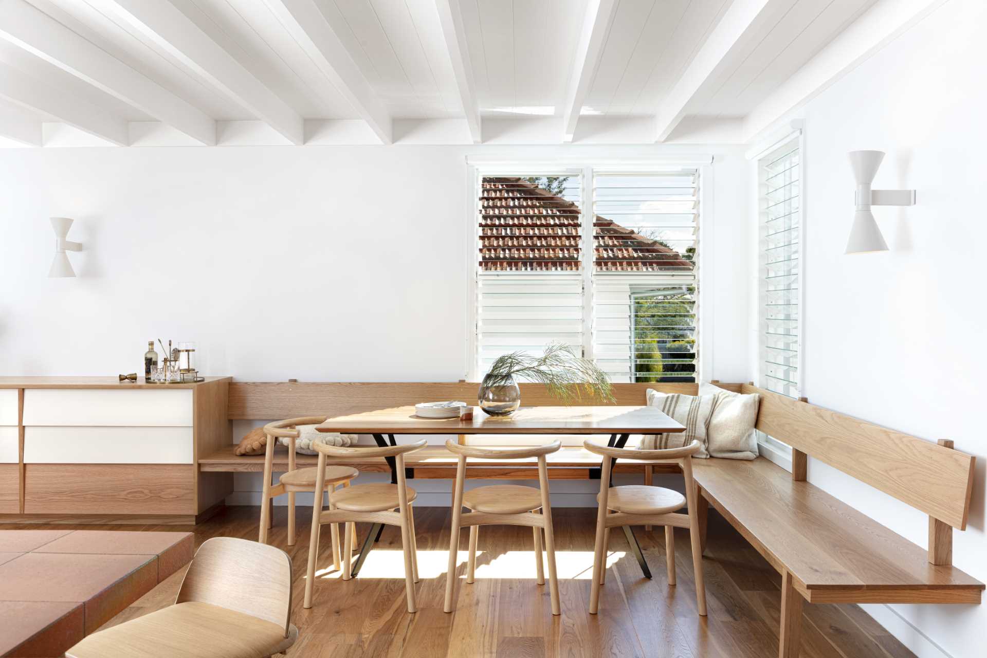 This open-plan dining room includes a wood banquette that wraps around the corner of the room, providing an abundance of seating.