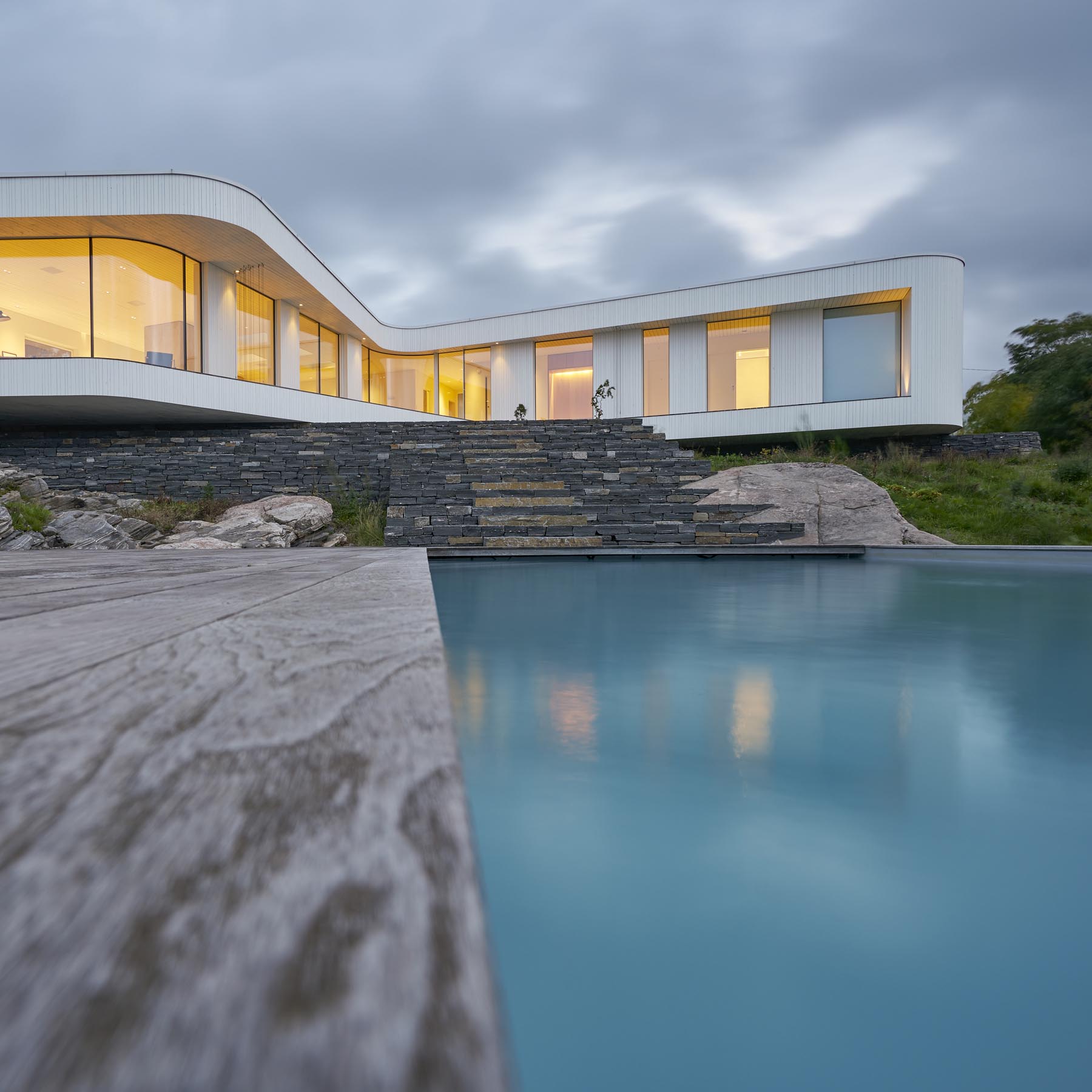 A modern house with a curved design, and a swimming pool.