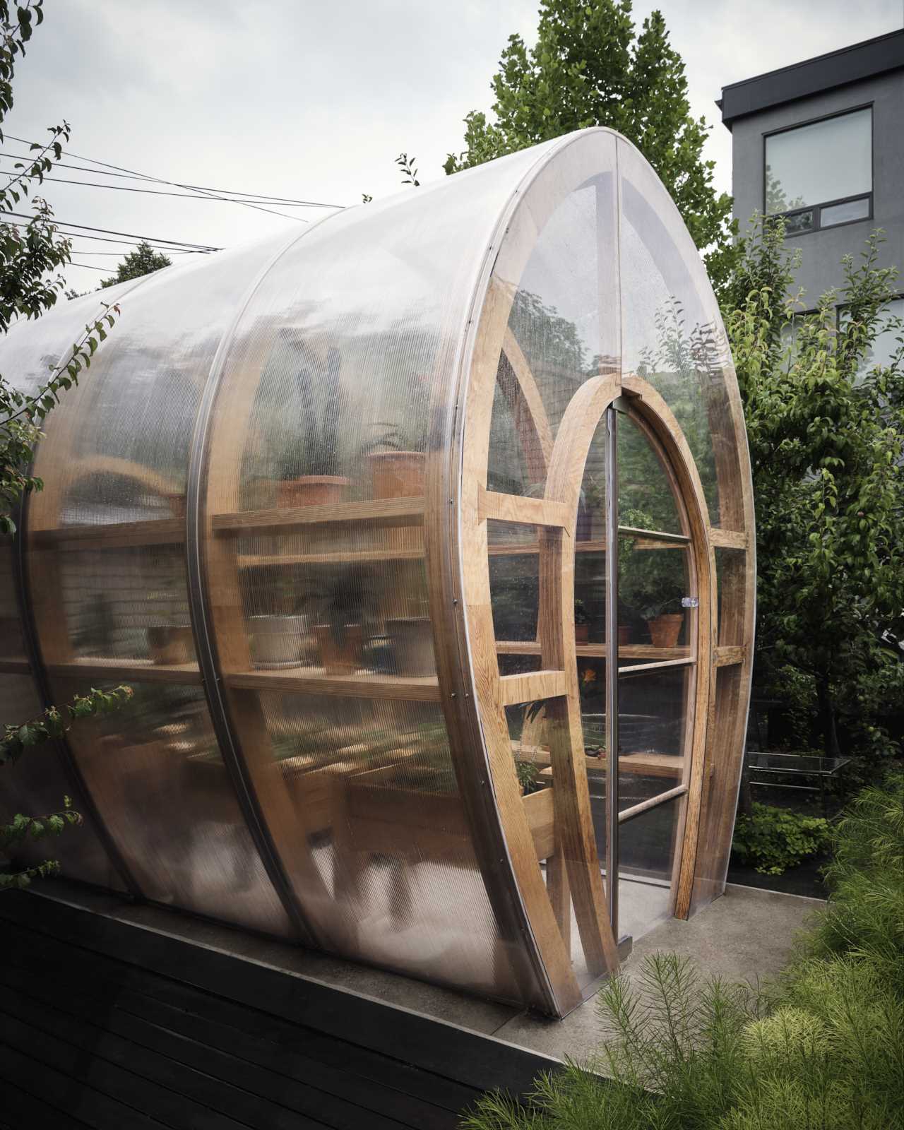 A modern and modular greenhouse design with a curved shape made from marine-grade plywood ribs and polycarbonate sheet.