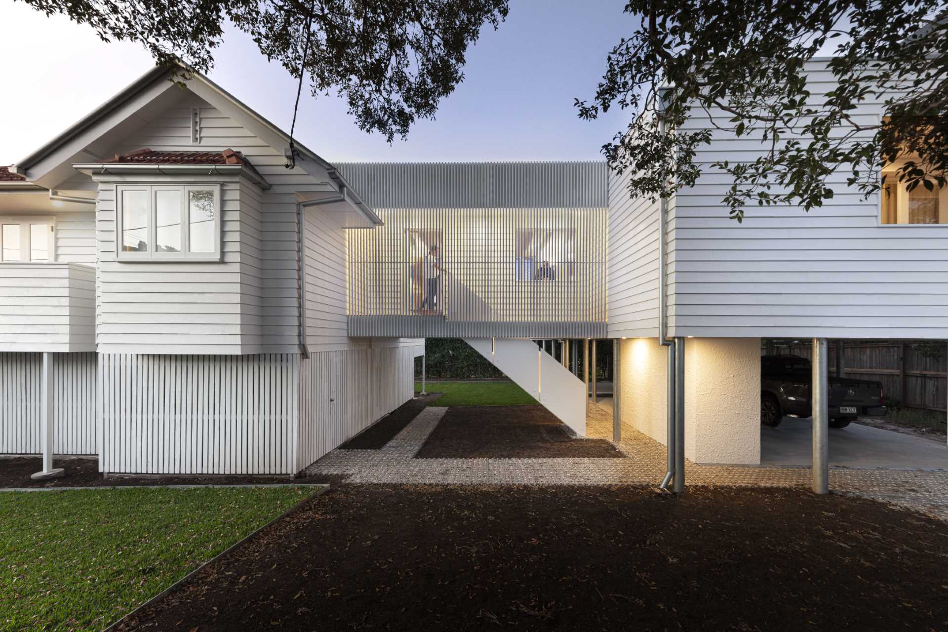 A walkway with windows, eases the transition between old and new, and includes stairs that lead up to the new entryway of the home.