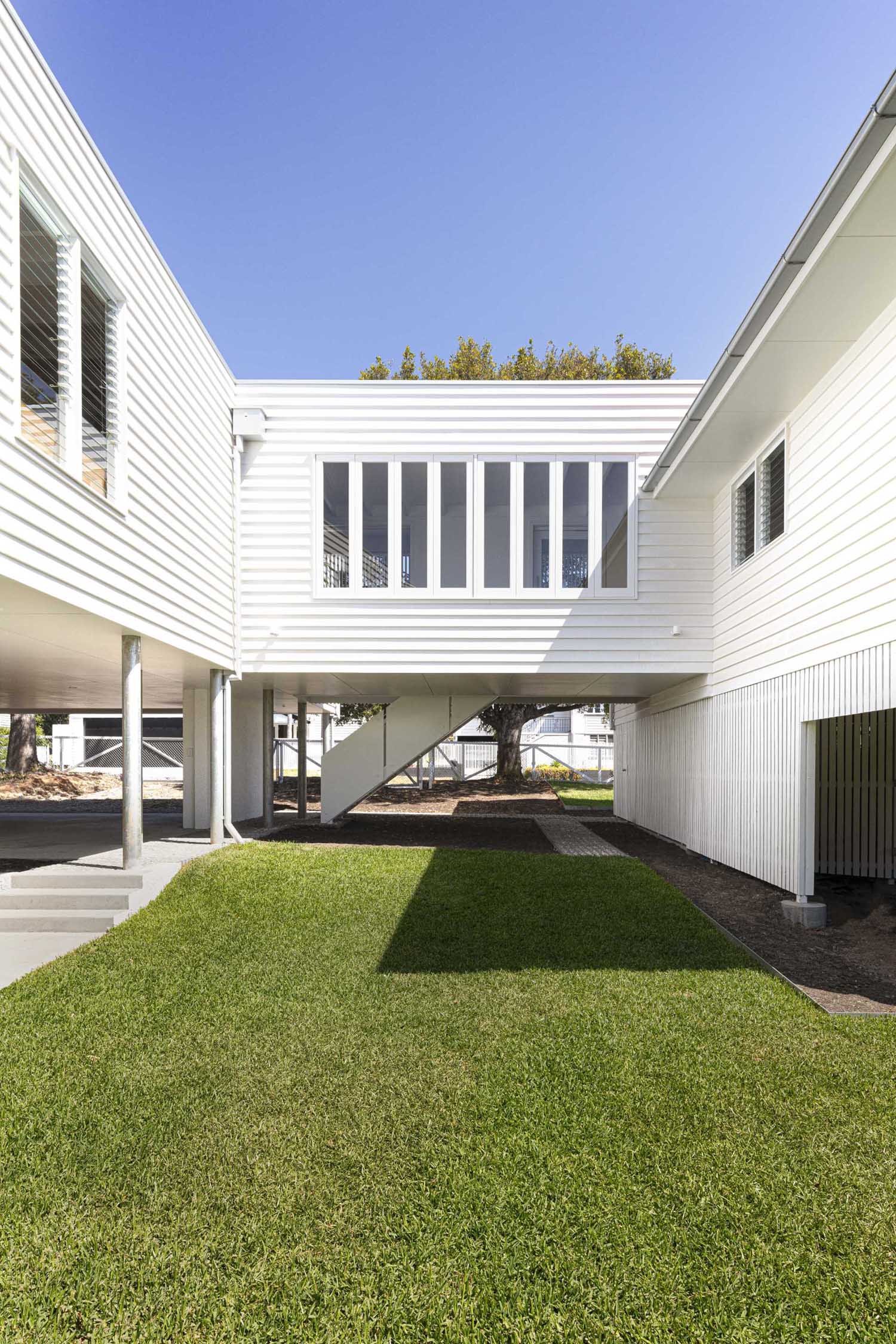 A walkway with windows, eases the transition between old and new, and includes stairs that lead up to the new entryway of the home.