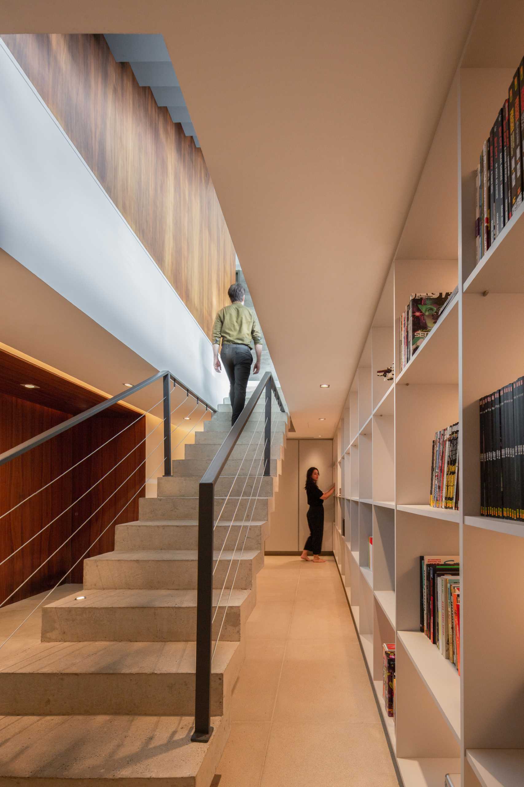 Concrete stairs lead down to a basement that has a wall of shelving with hidden lighting.