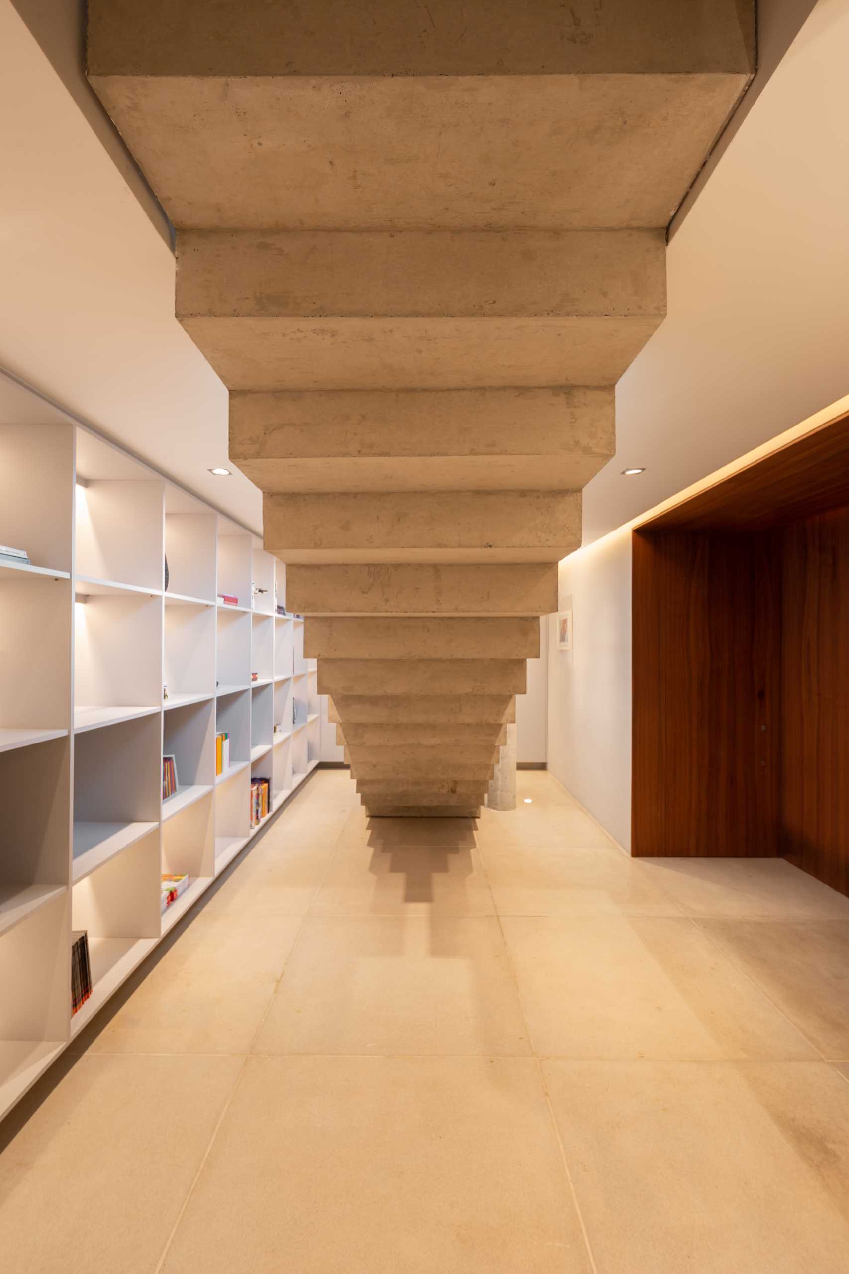 Concrete stairs lead down to a basement that has a wall of shelving with hidden lighting.
