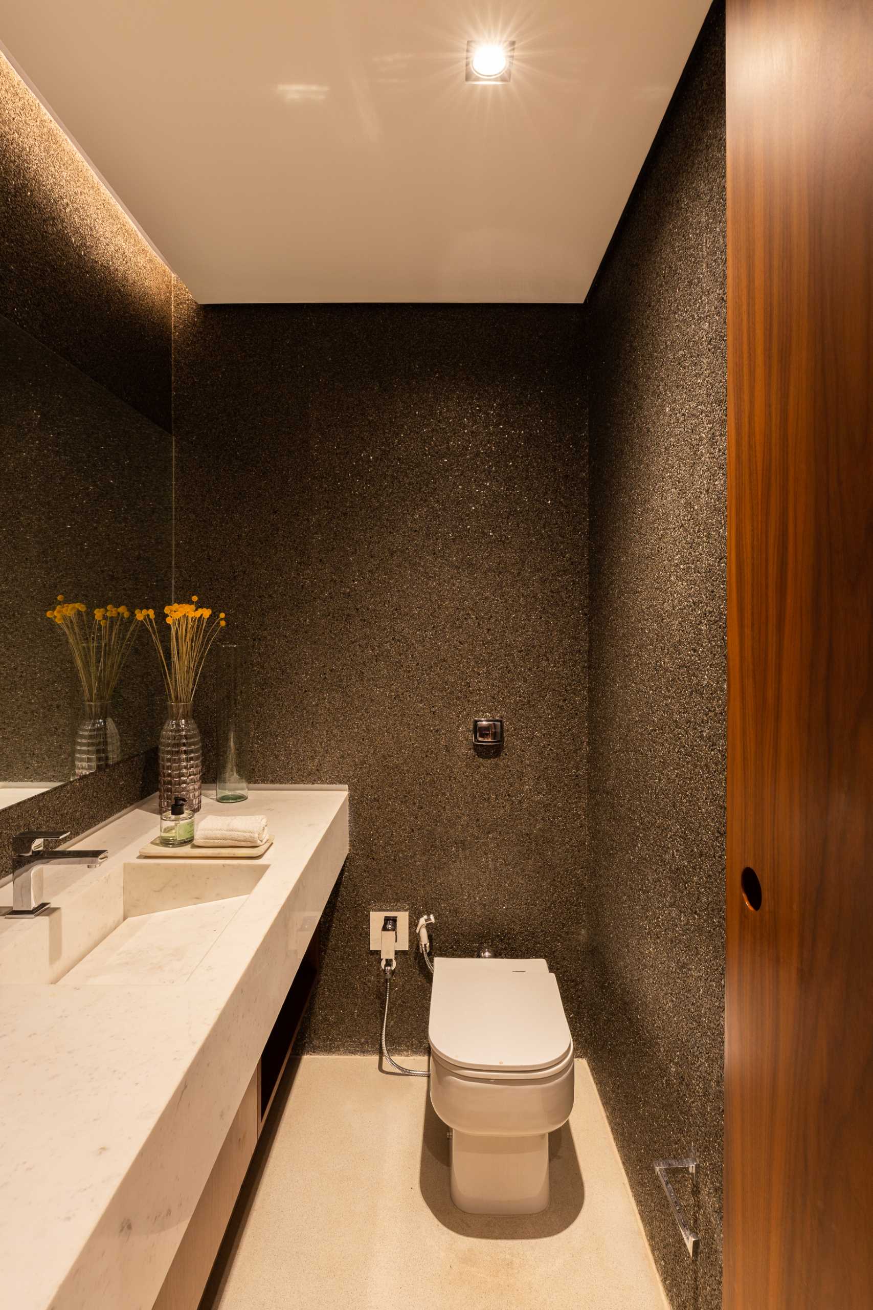 A powder room with dark walls and hidden lighting.