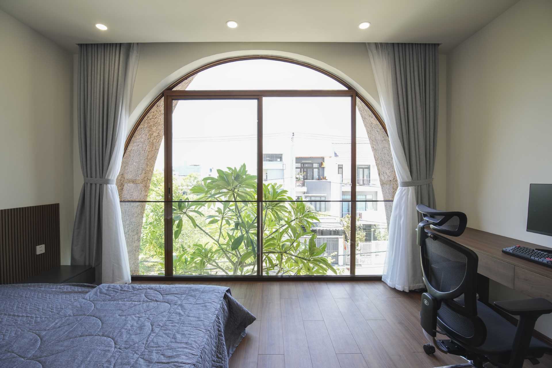 A simple bedroom with an arched window and a balcony.