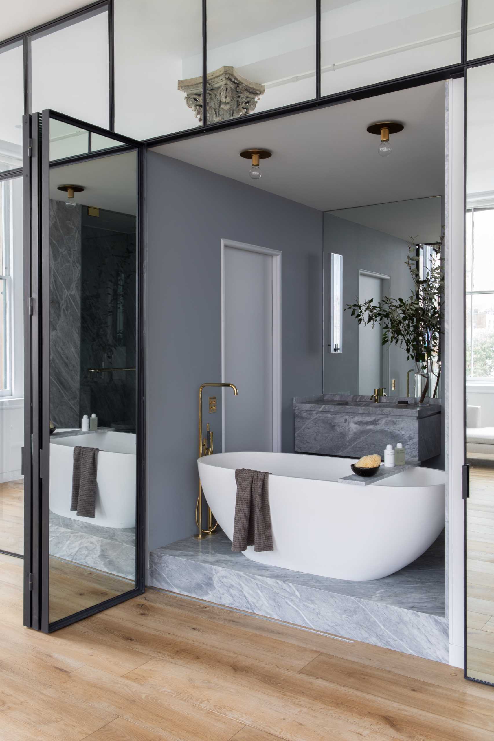 Inside this modern bathroom, there's a monobloc oval tub is encased in walls of softly-veined stone.