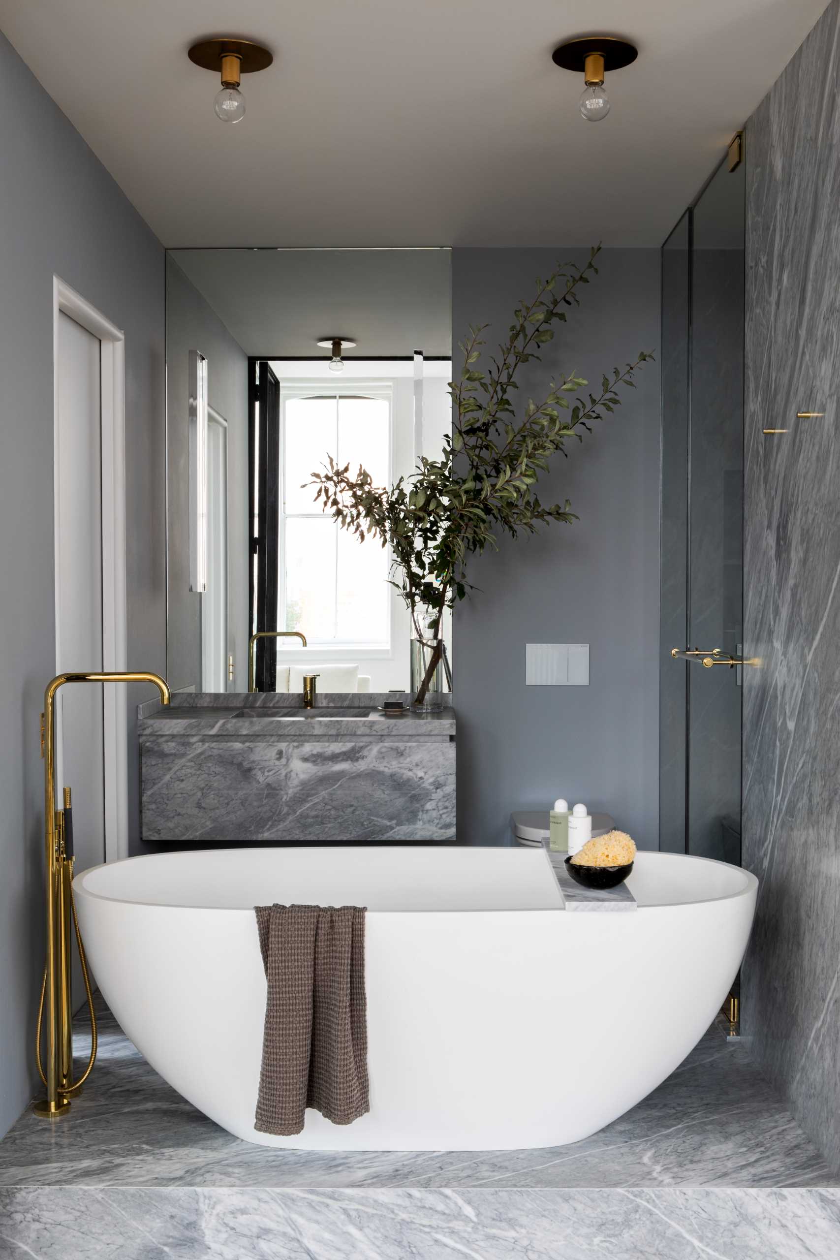 Inside this modern bathroom, there's a monobloc oval tub is encased in walls of softly-veined stone.