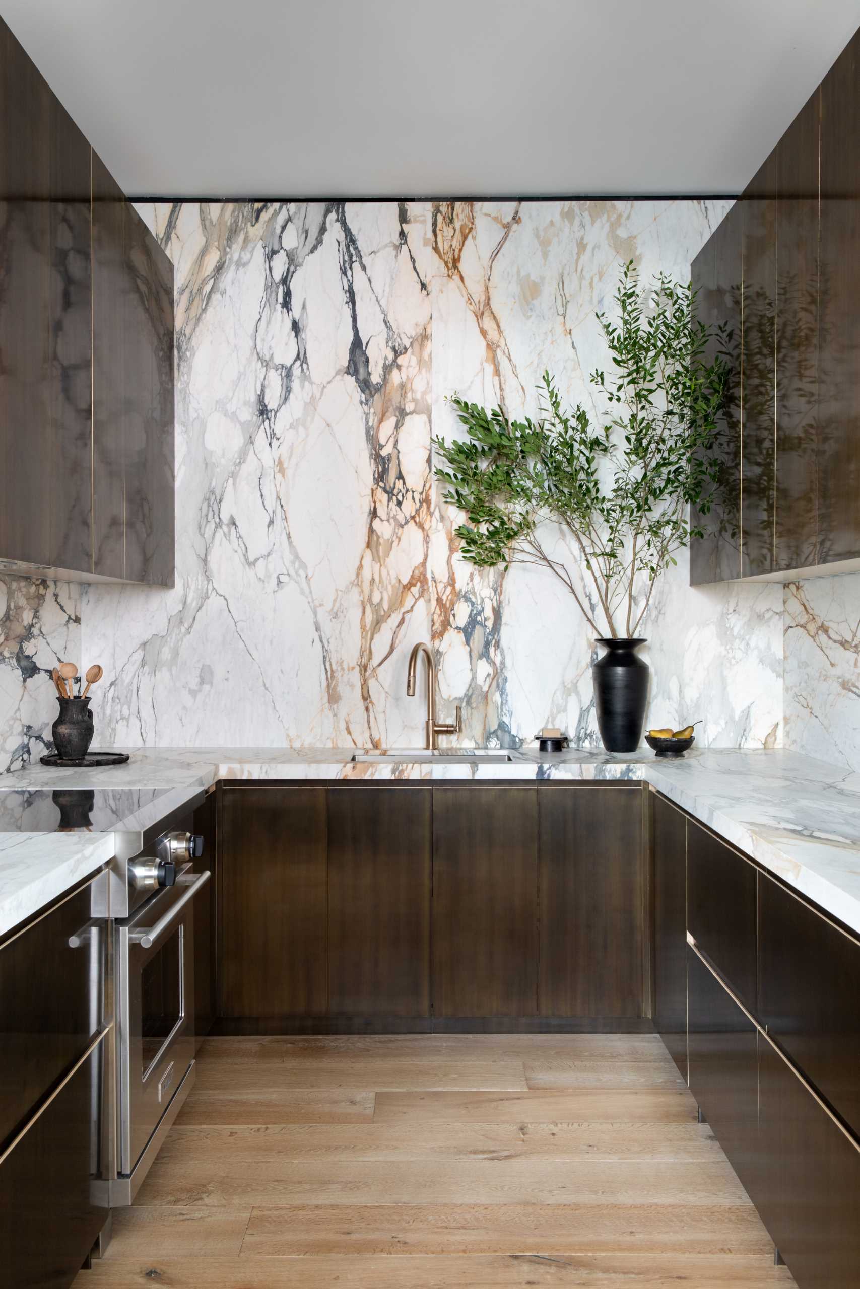 A modern kitchen includes matte figurative marble and patinated brass millwork.