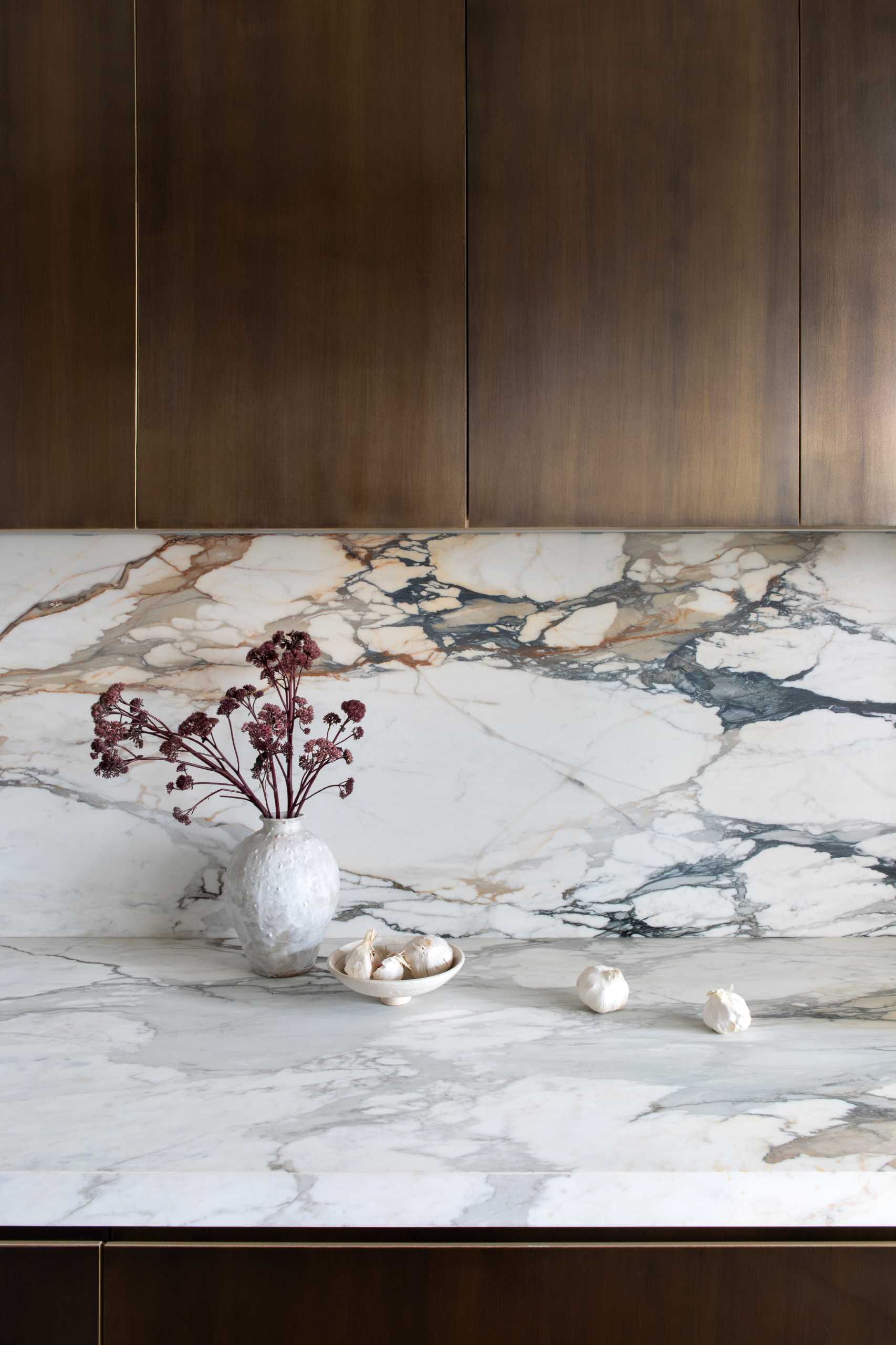 A modern kitchen includes matte figurative marble and patinated brass millwork.