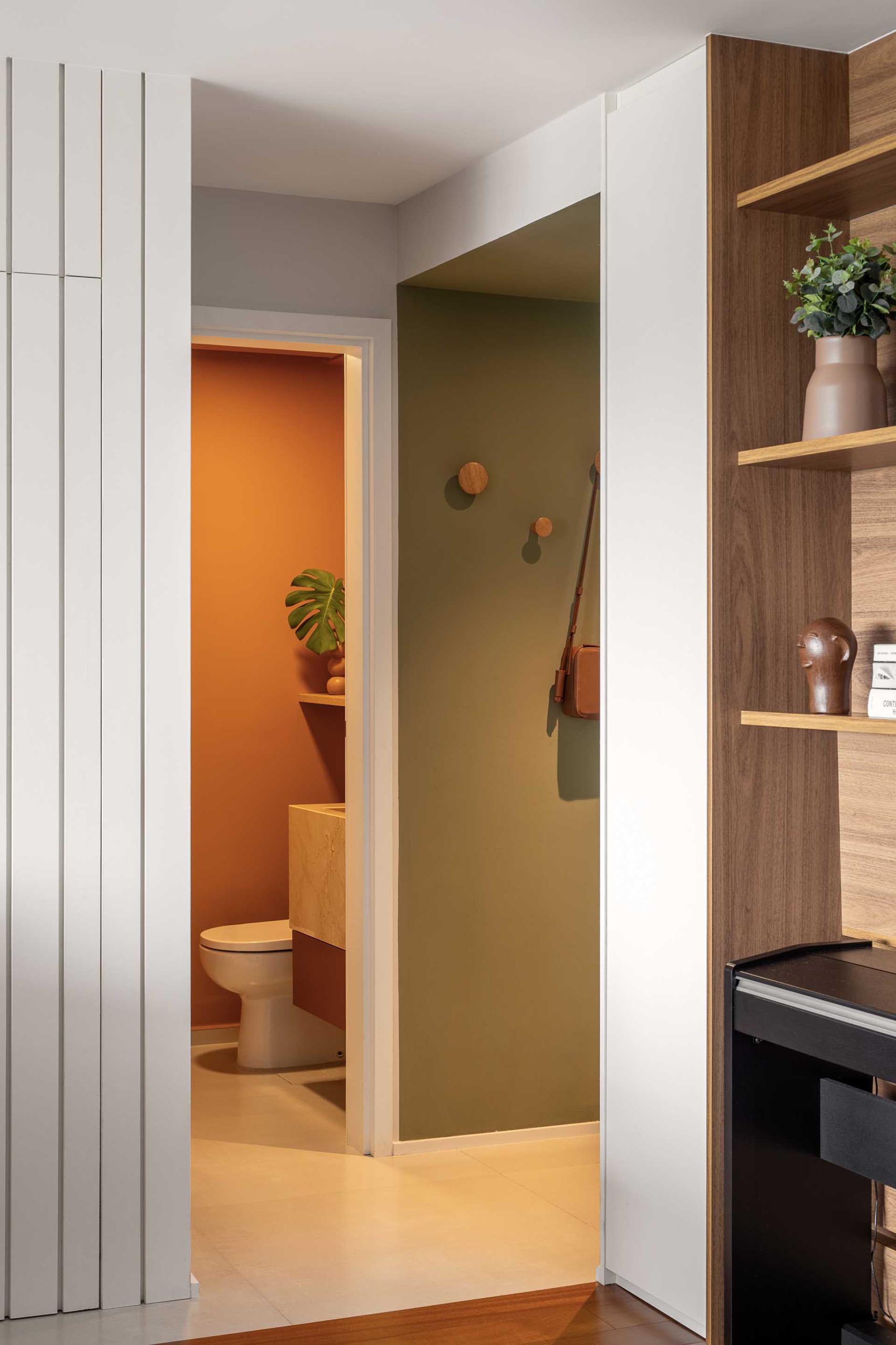 A modern powder room with matte terracotta colored walls.