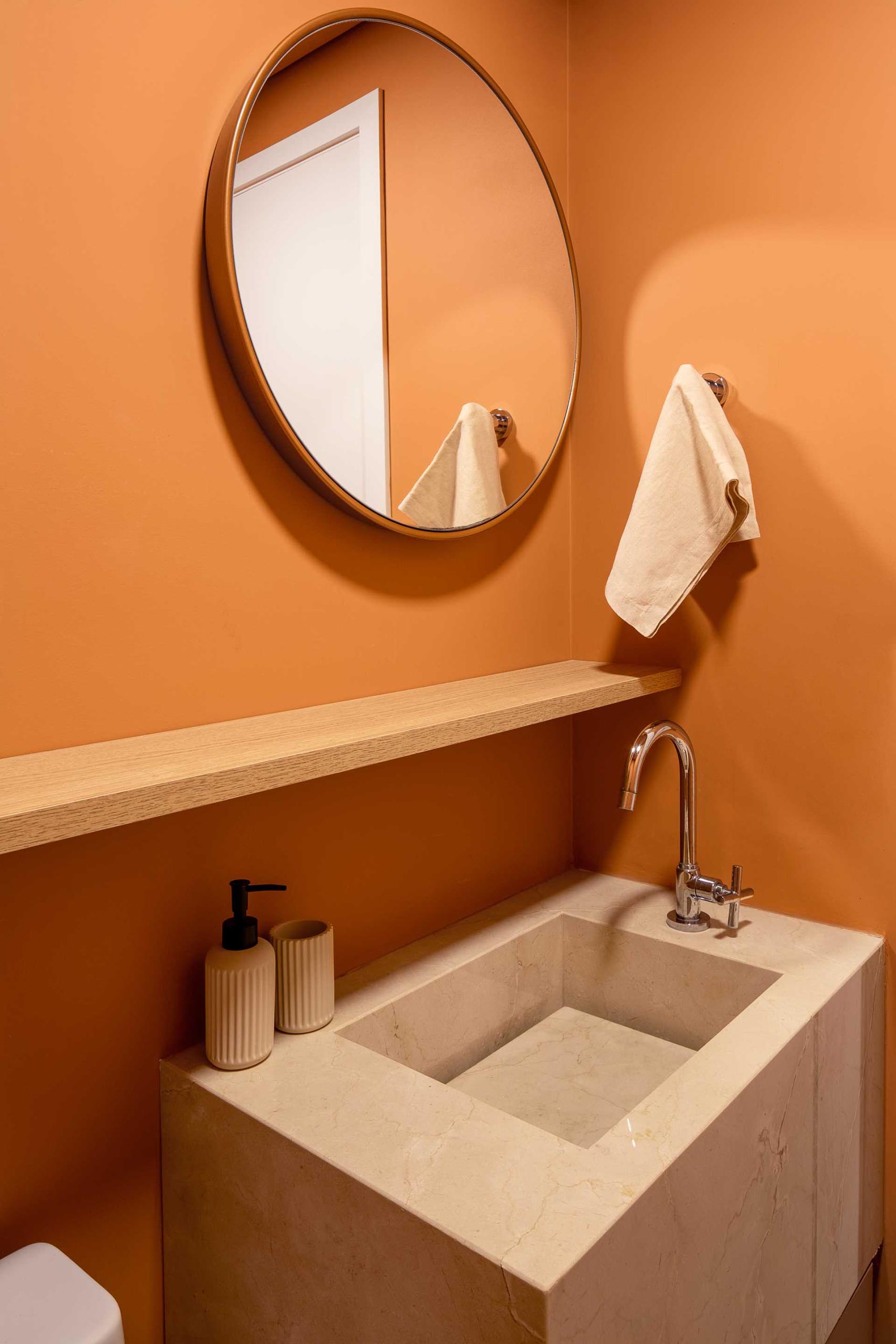 A modern powder room with matte terracotta colored walls.