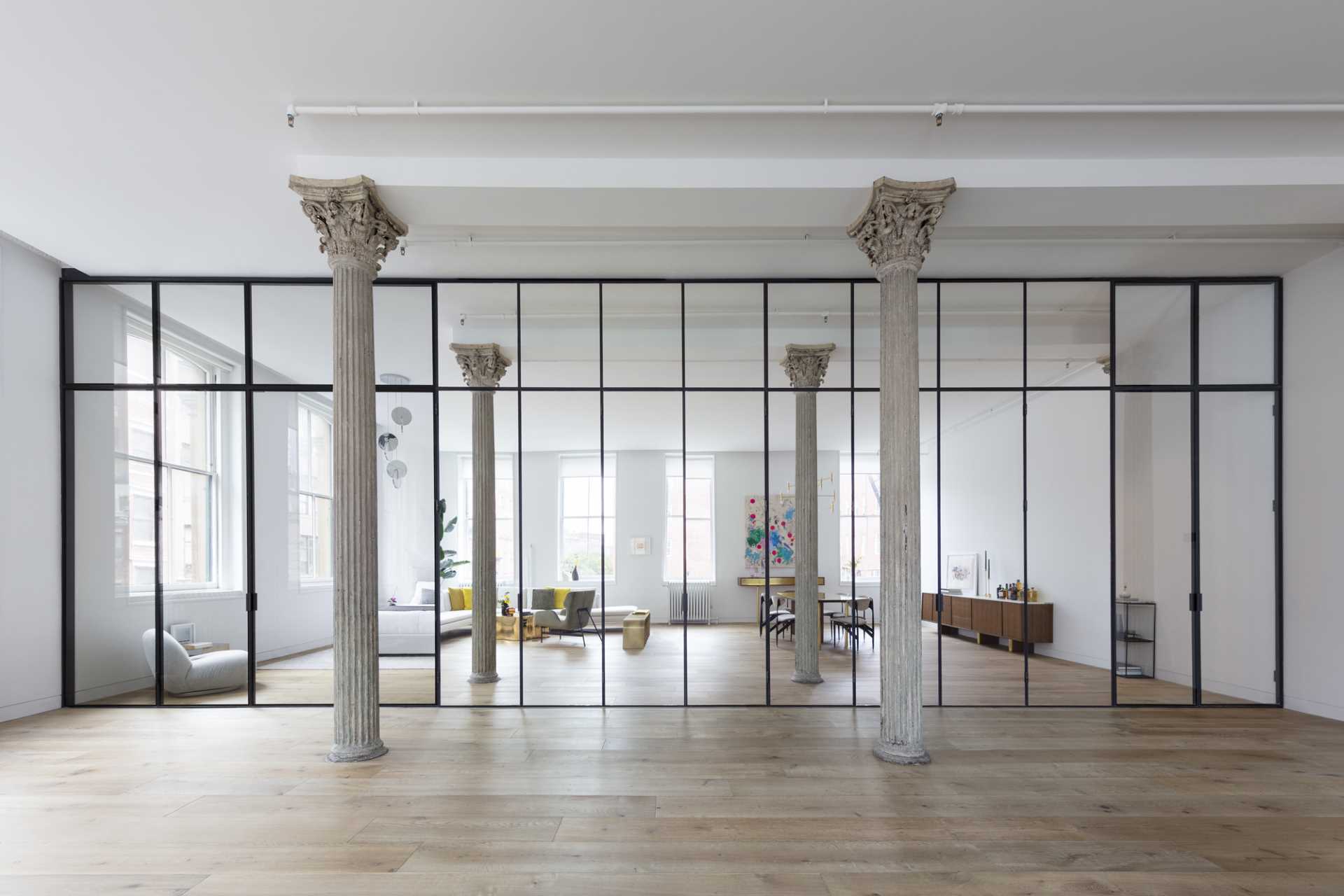 Key to the design of this updated loft apartment, is a wall of floor-to-ceiling, black-framed glass that includes a combination of clear glass and mirrored panels. 