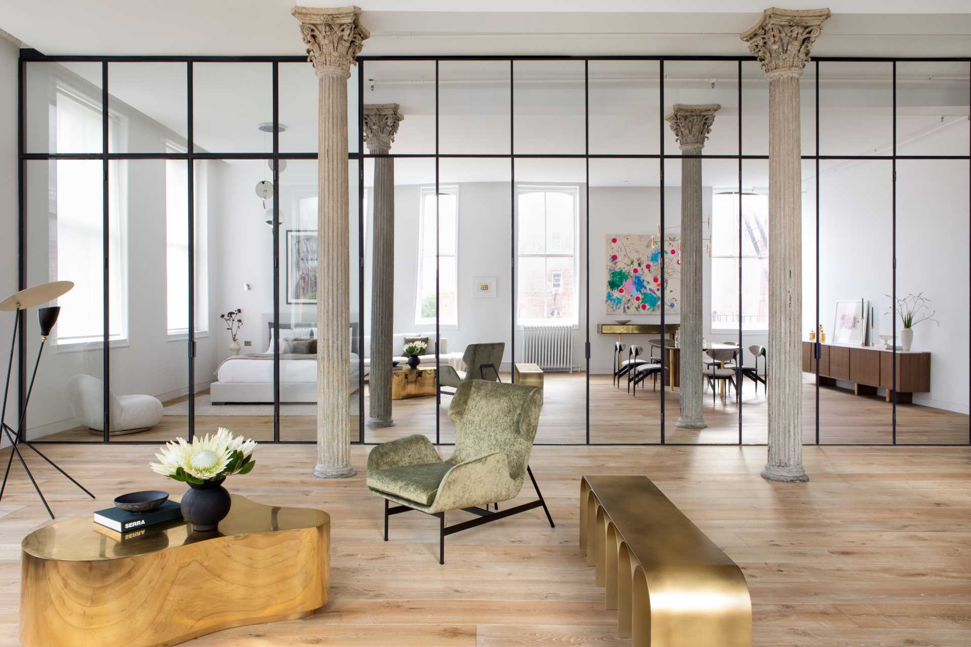 Key to the design of this updated loft apartment, is a wall of floor-to-ceiling, black-framed glass that includes a combination of clear glass and mirrored panels. 