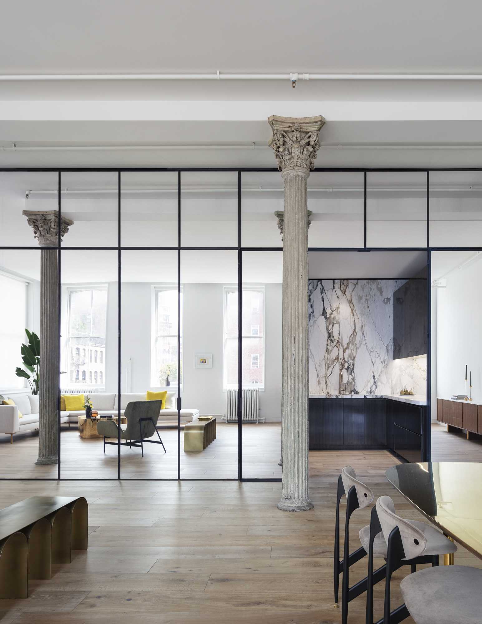 A mirrored set of doors opens into the kitchen where matte figurative marble and patinated brass millwork play off of the loft’s new wide-plank oak floors.