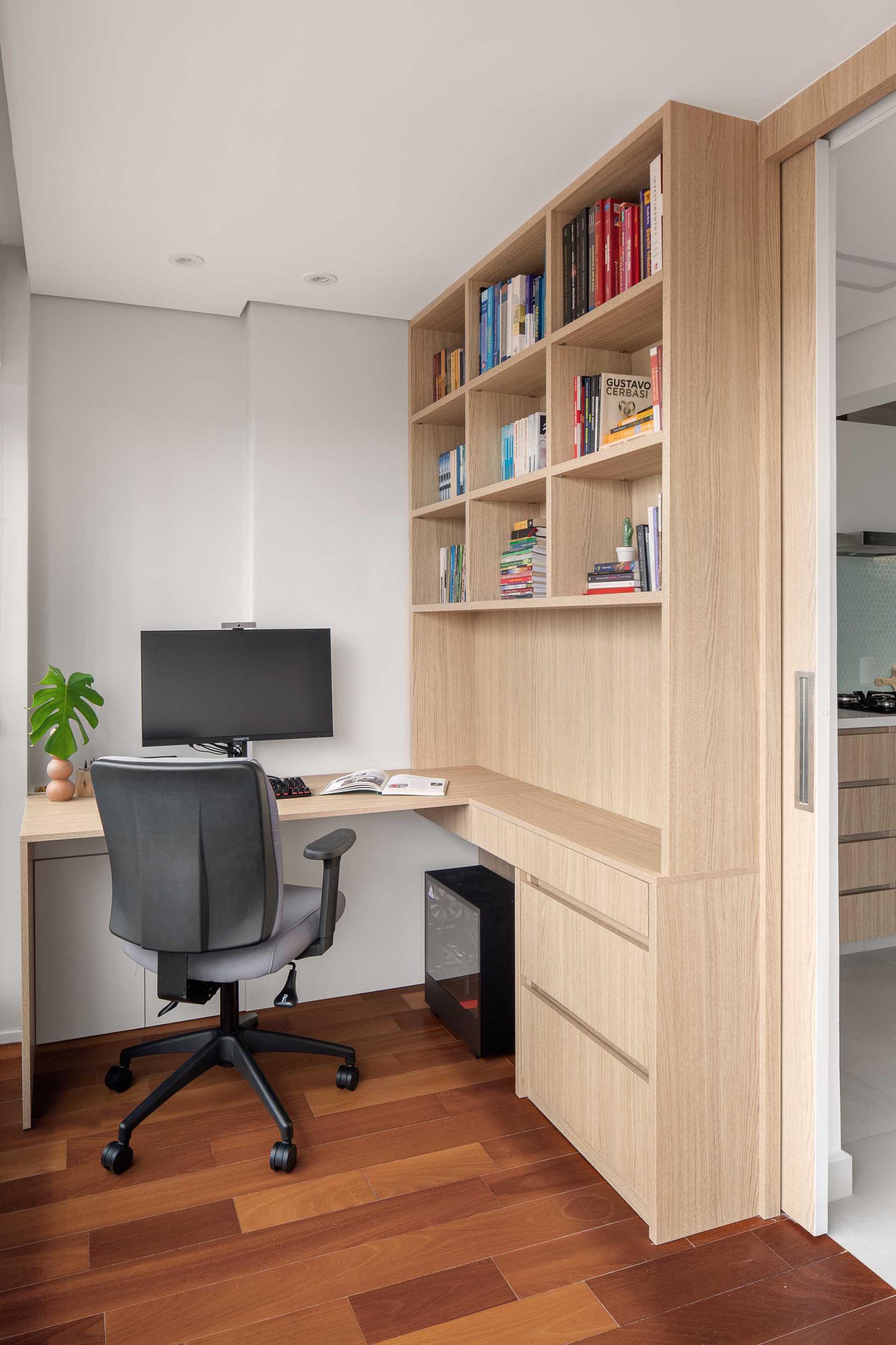 This home office includes a custom designed desk that lines the wall and connects with a bookshelf and drawers.