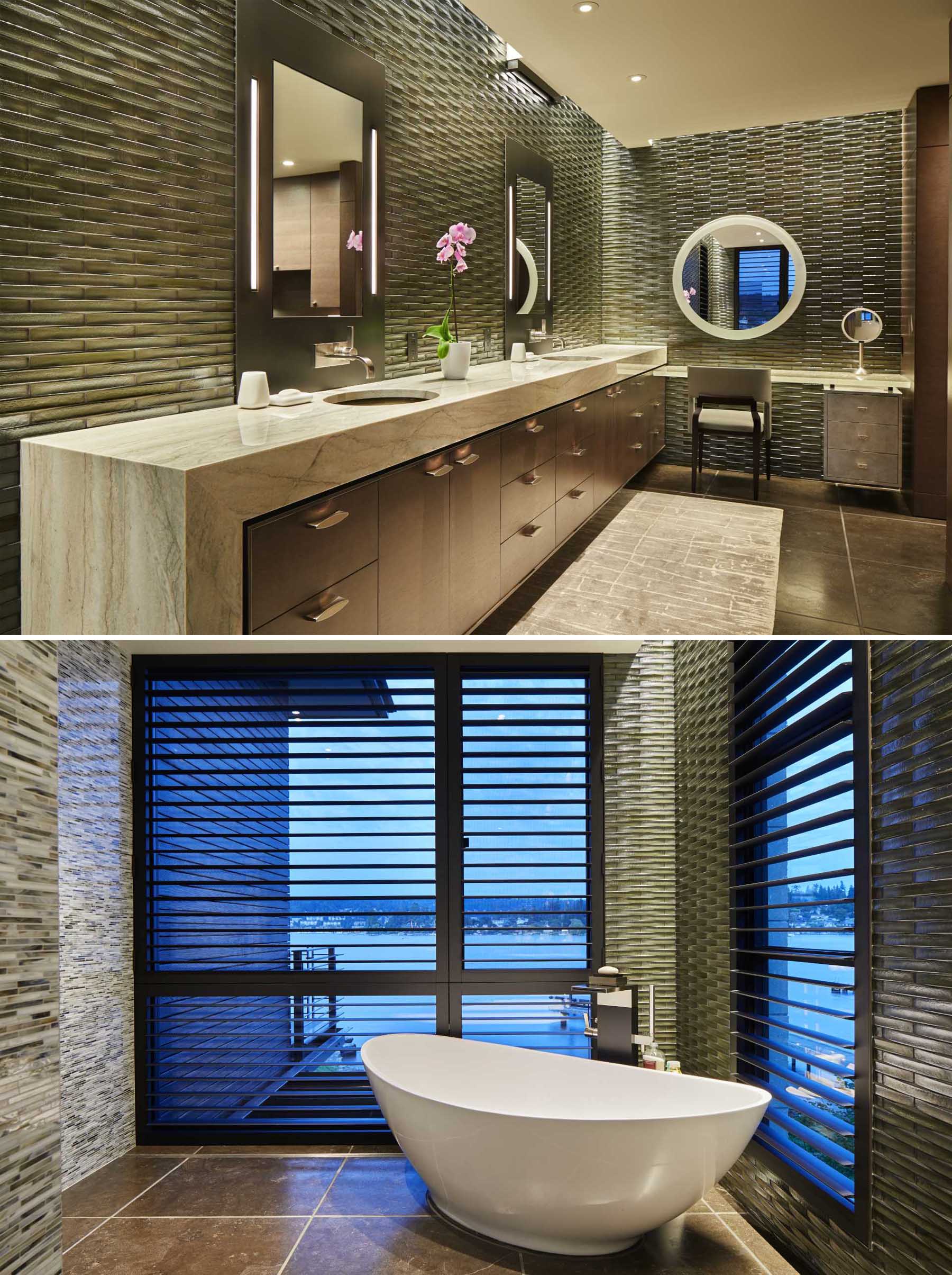 In this bathroom, the walls are lined with textured tiles, while the double vanity has plenty of counterspace. At the end of the vanity, there's a freestanding bathtub with views of the lake.