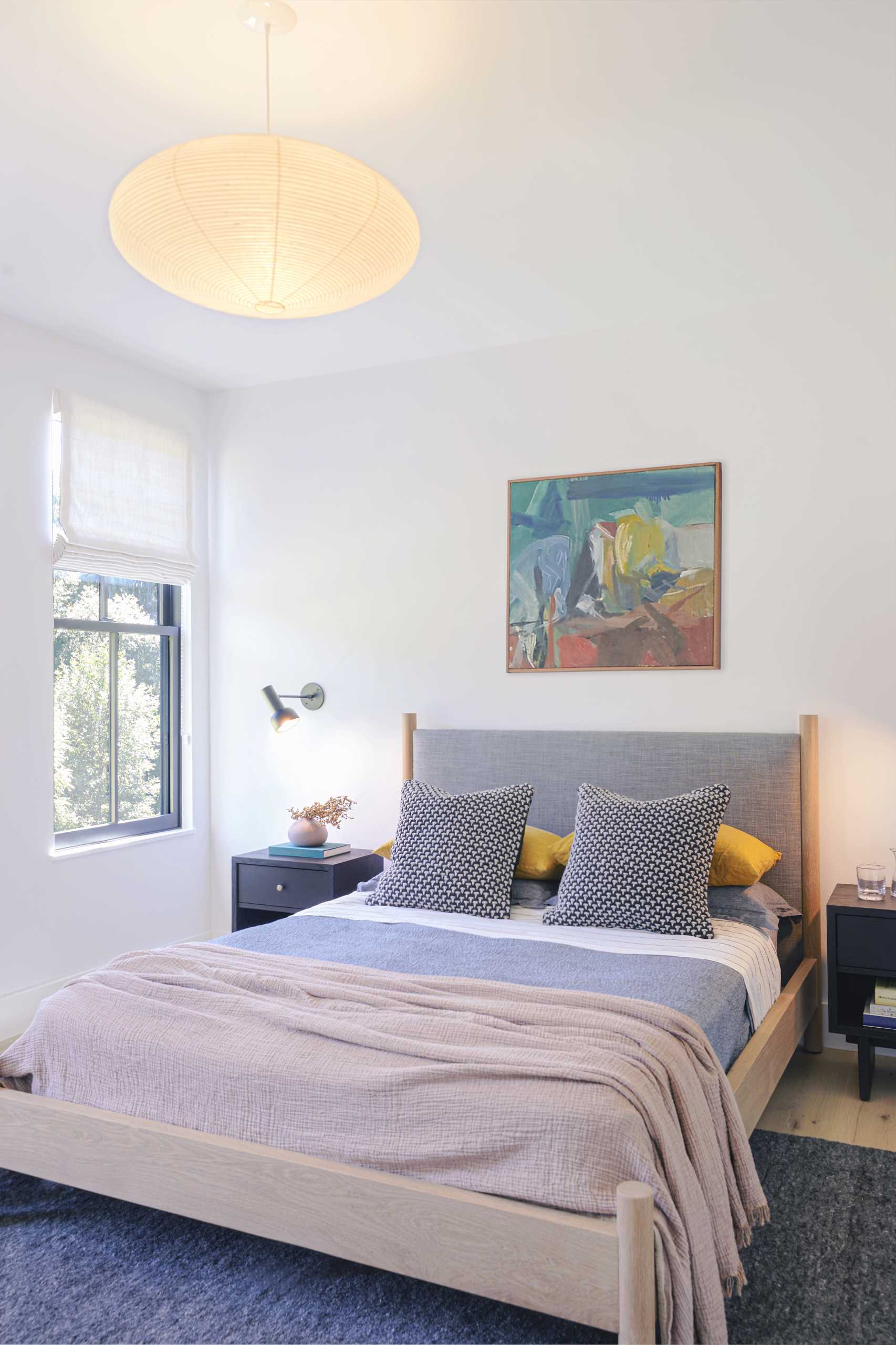 A modern bedroom with light colored walls and a wood bed frame.