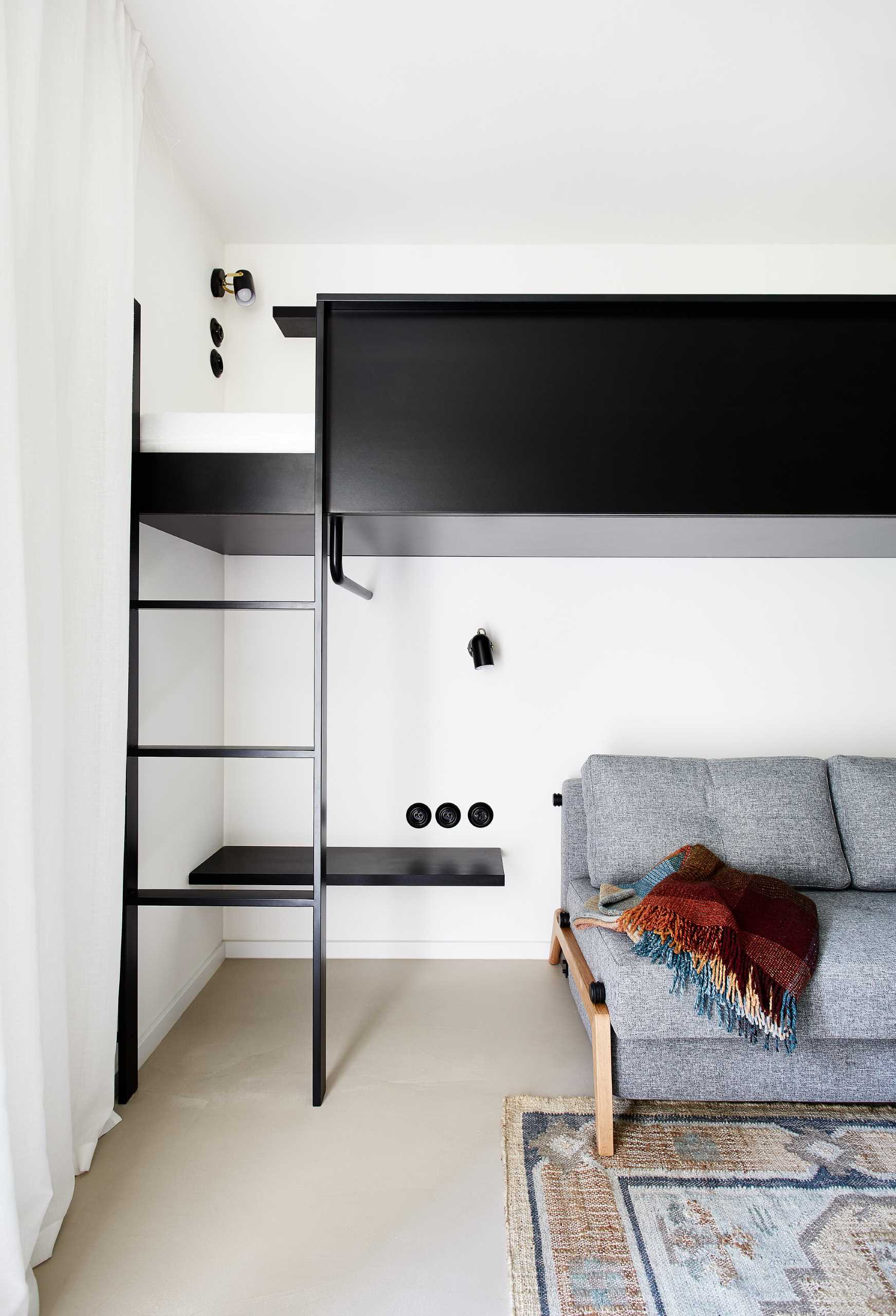 This modern bedroom includes two loft beds in a black frame. Underneath, there's a comfortable couch with two side tables. The couch can also be transformed into an additional bed.