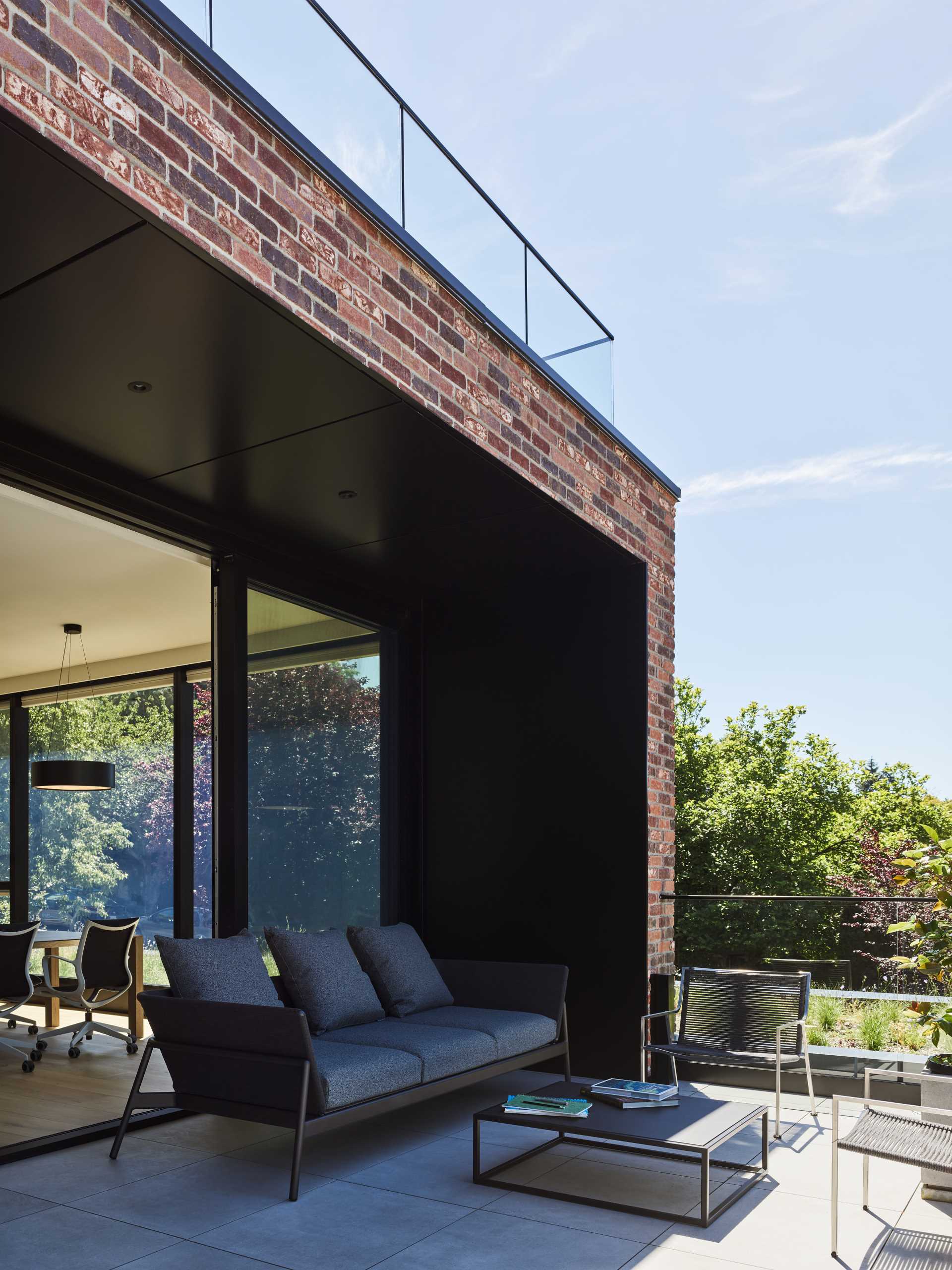 A modern brick house with black window frames and patio.