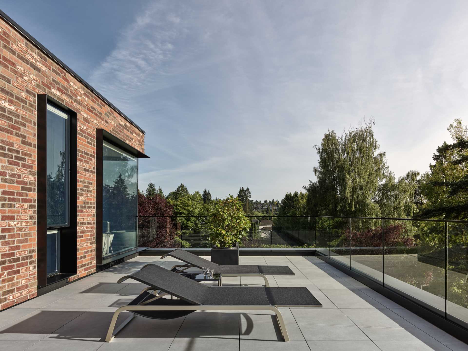 A modern brick house with black window frames and patio.