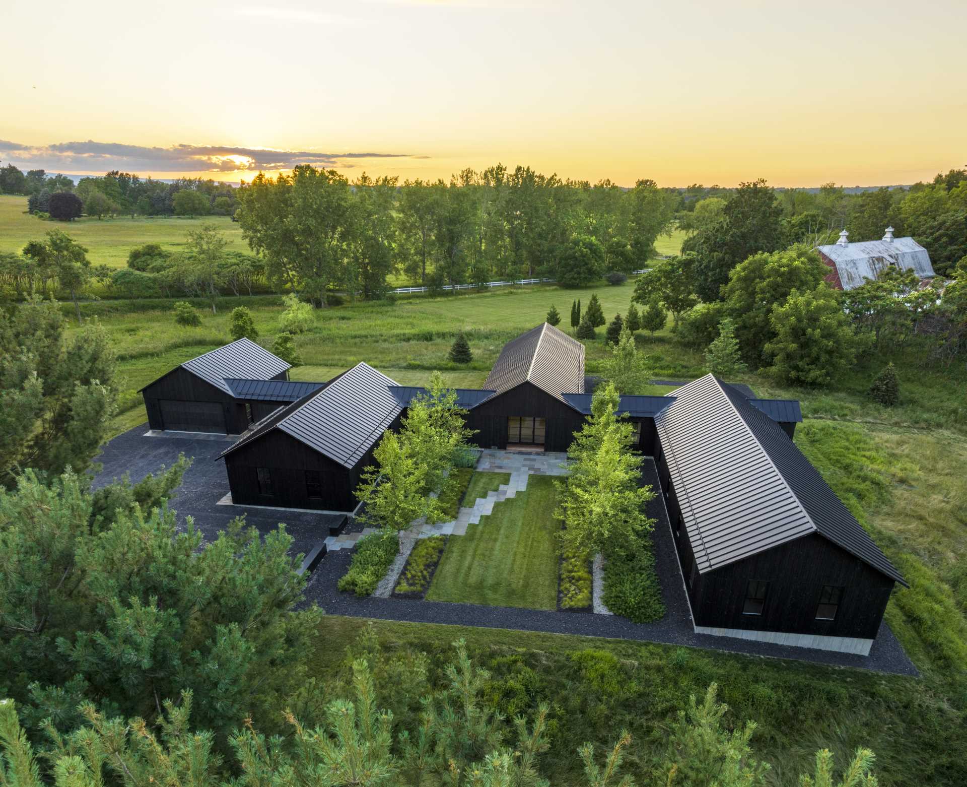 A modern house with standing seam roofing, black stained vertical cedar siding, and single-story gables with identical pitches.