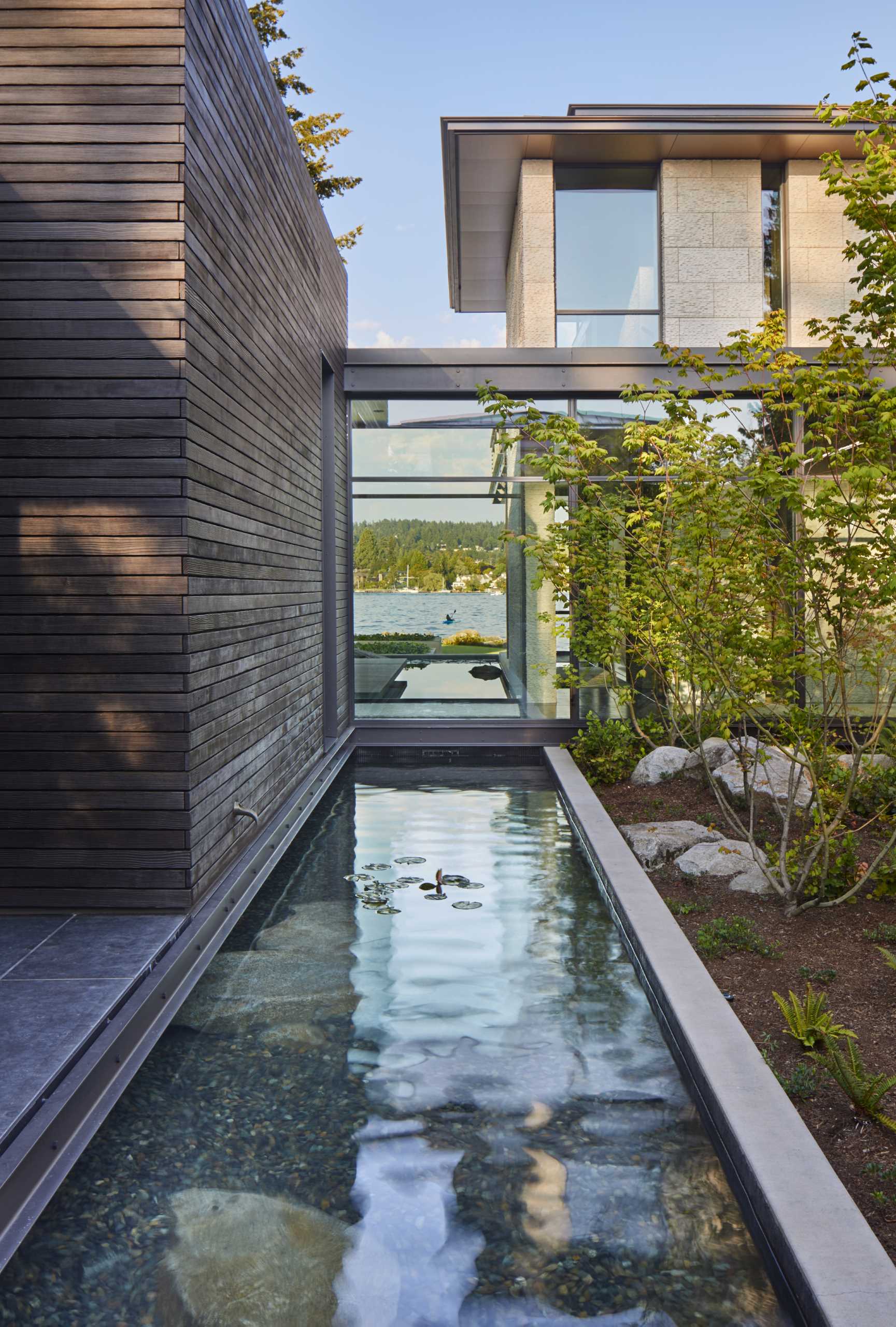 A modern house with water features that flow beneath some parts of the home.