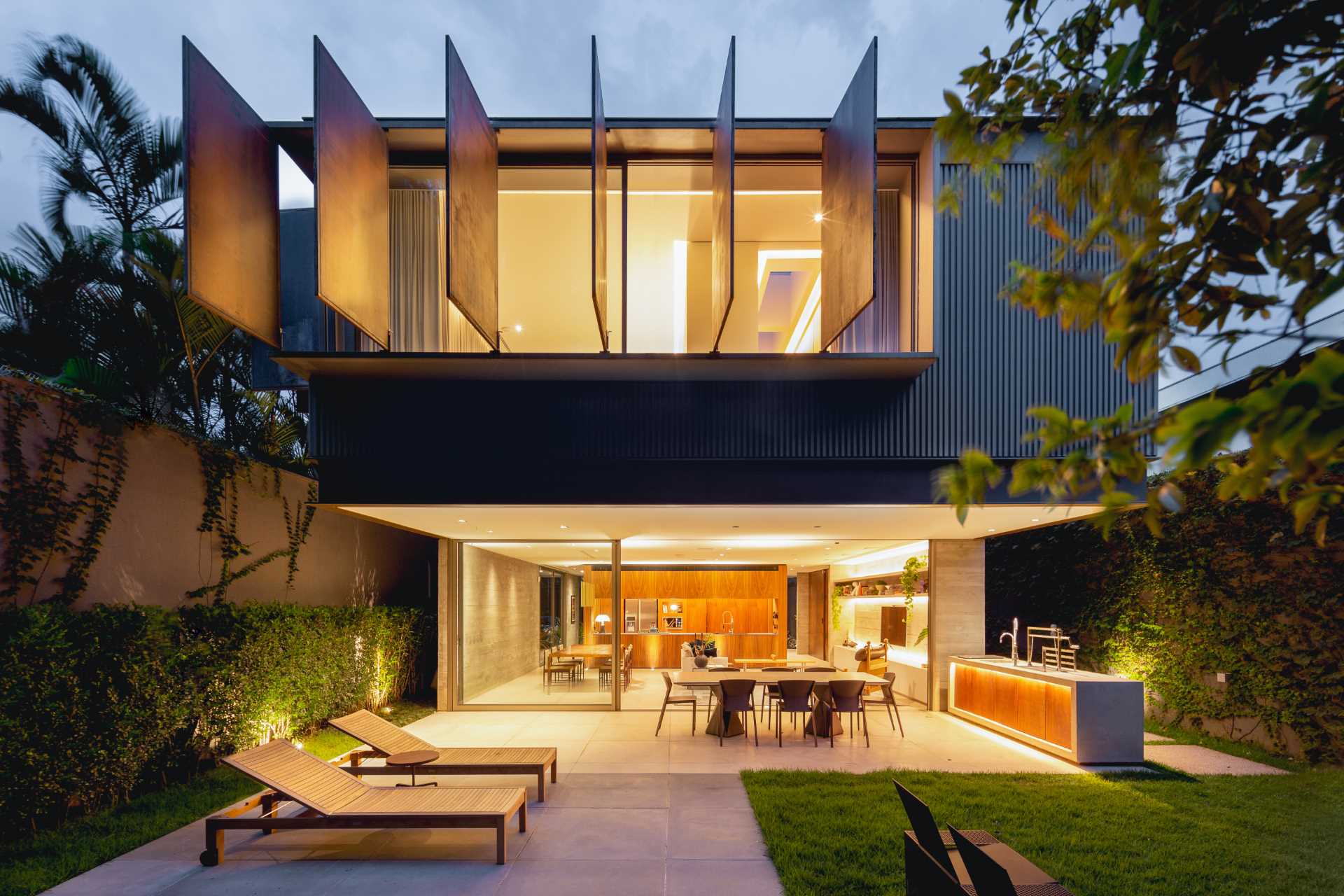 A modern home with large metal shutters on the upper level.