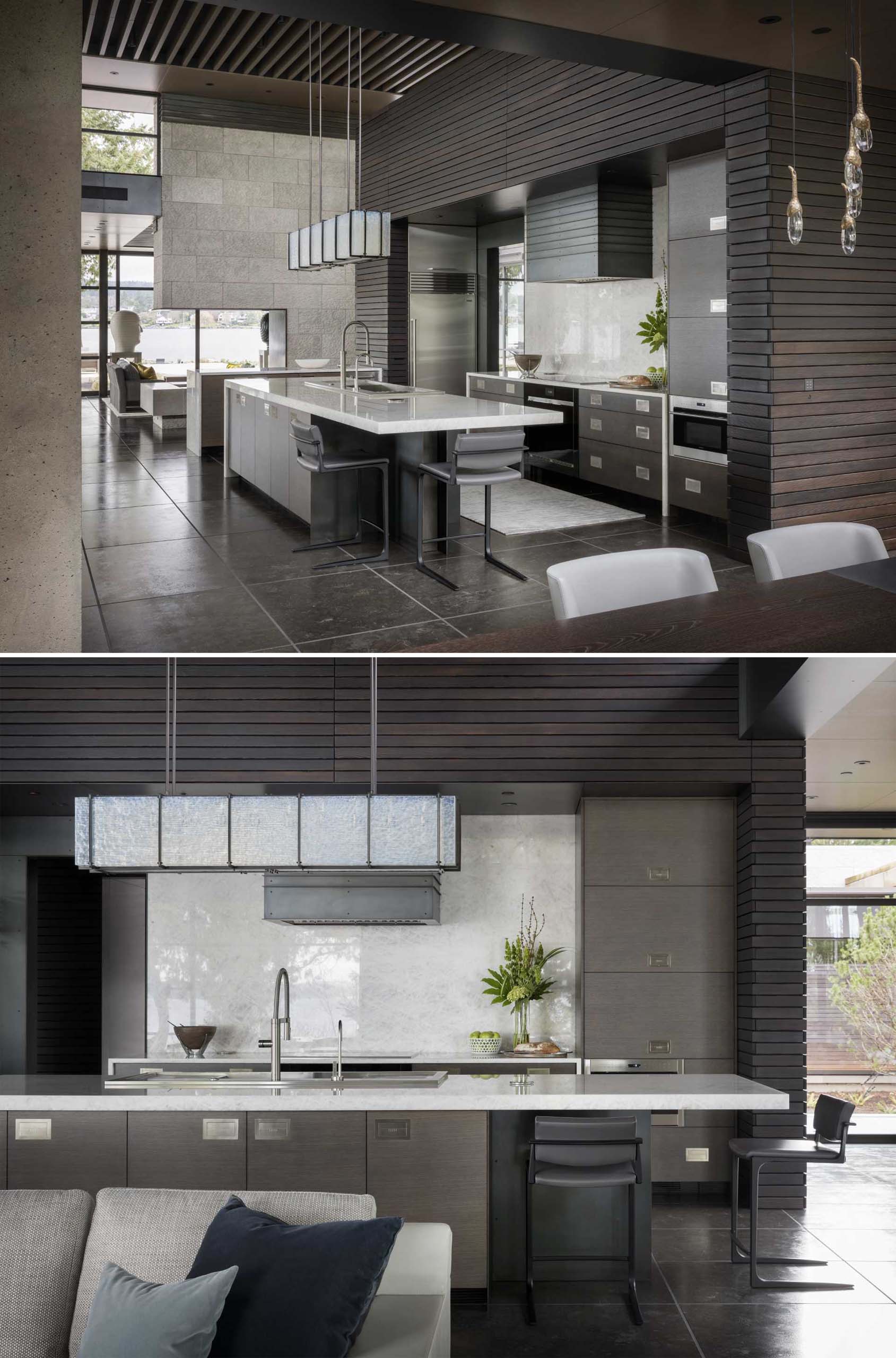 In this modern kitchen, there's a large island and a dark wall accent wall that continues into the dining room.