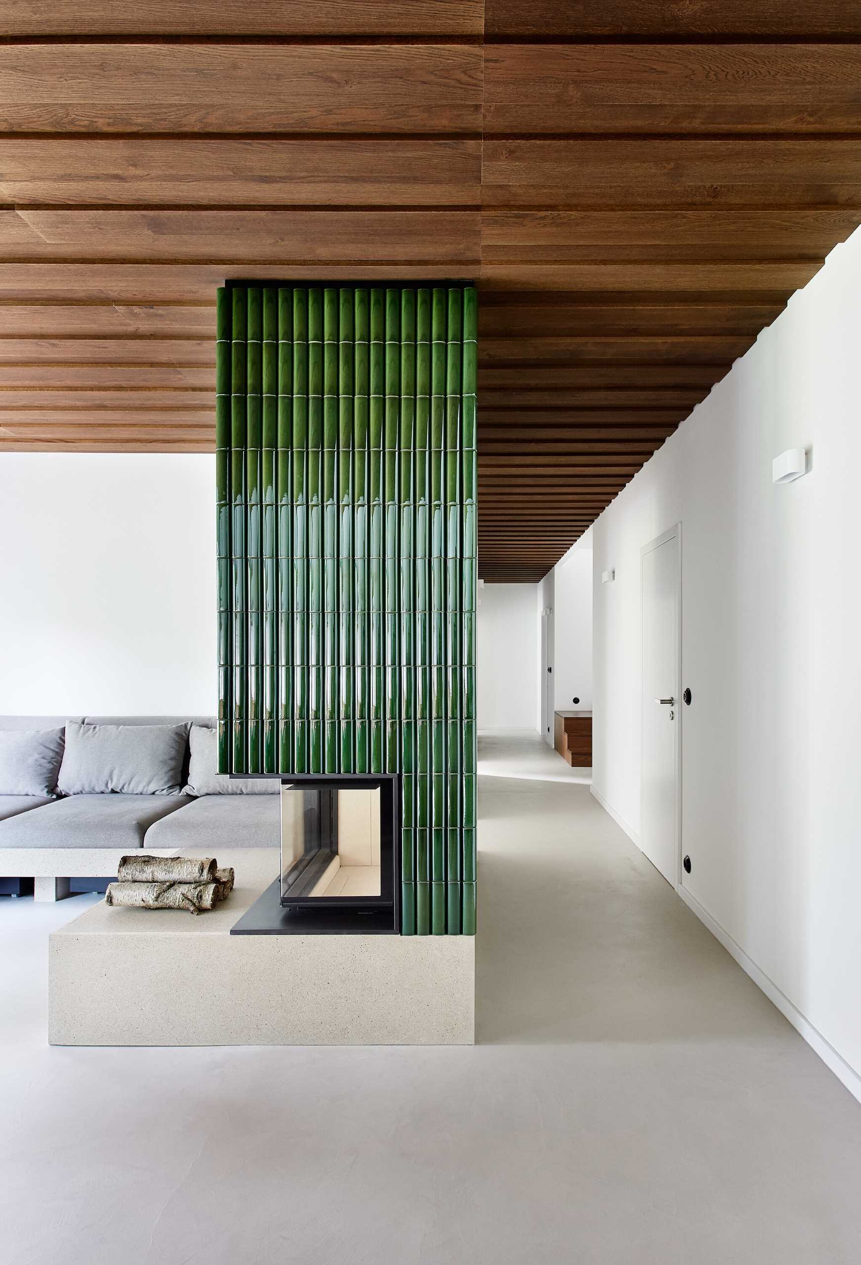 Located between the living room, with its built-in couch, and the hallway, the green tiles of the fireplace are handmade ceramic tiles that have a rounded design to them.