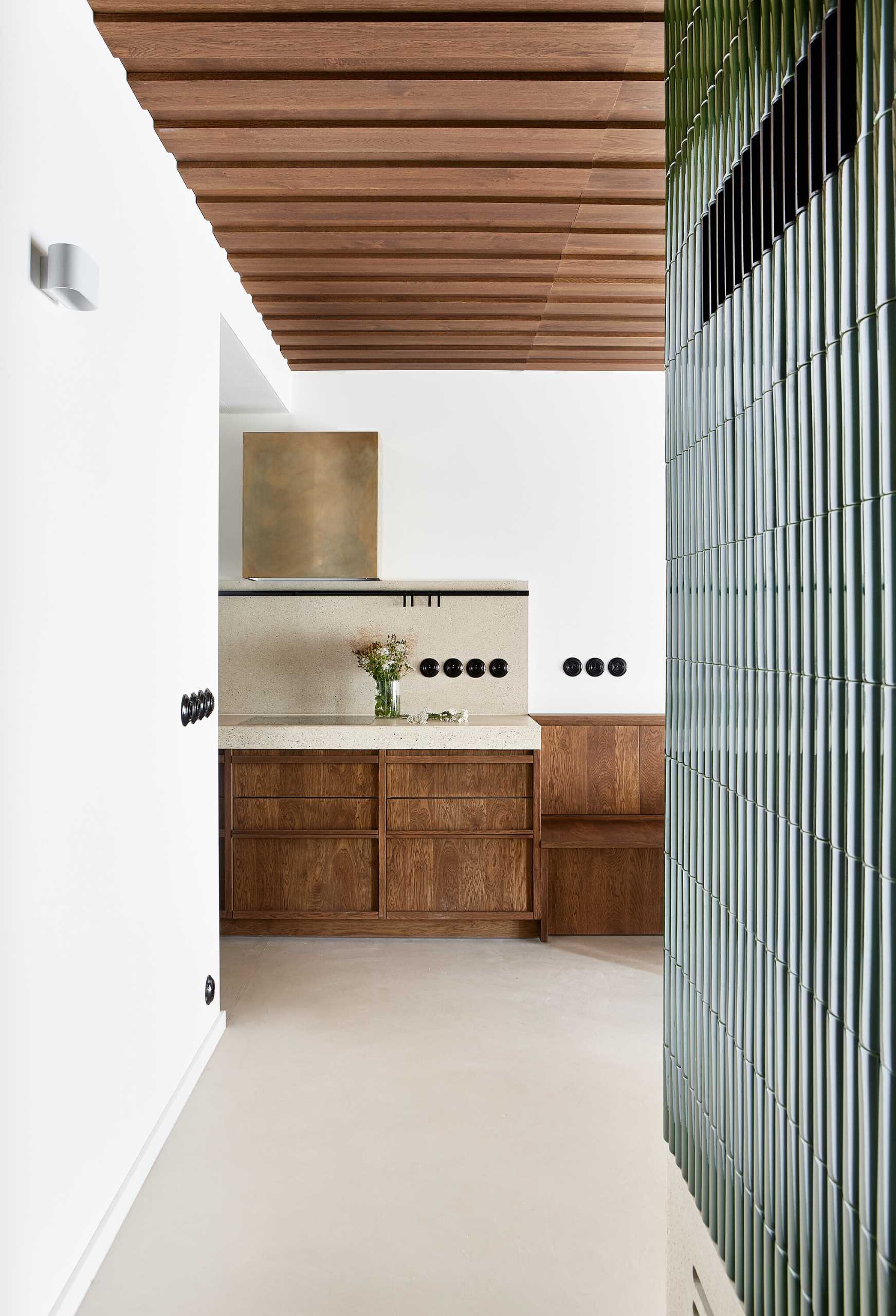 Rounded green tiles cover the exterior of a fireplace, while a wood ceiling adds warmth to the room.