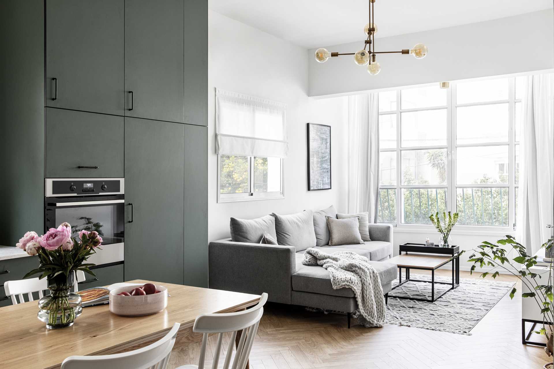 Uma sala de estar moderna com muita luz natural, um sofá cinza e plantas.