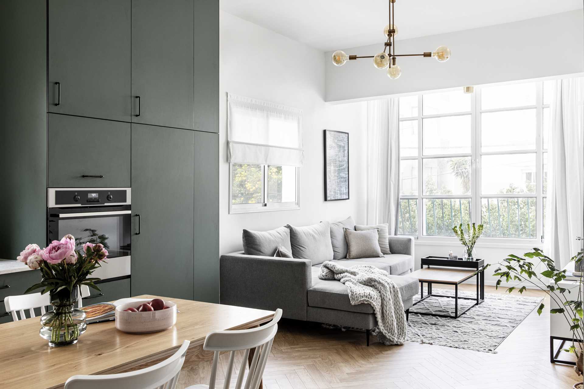 A modern living room with plenty of natural light, a grey couch, and plants.