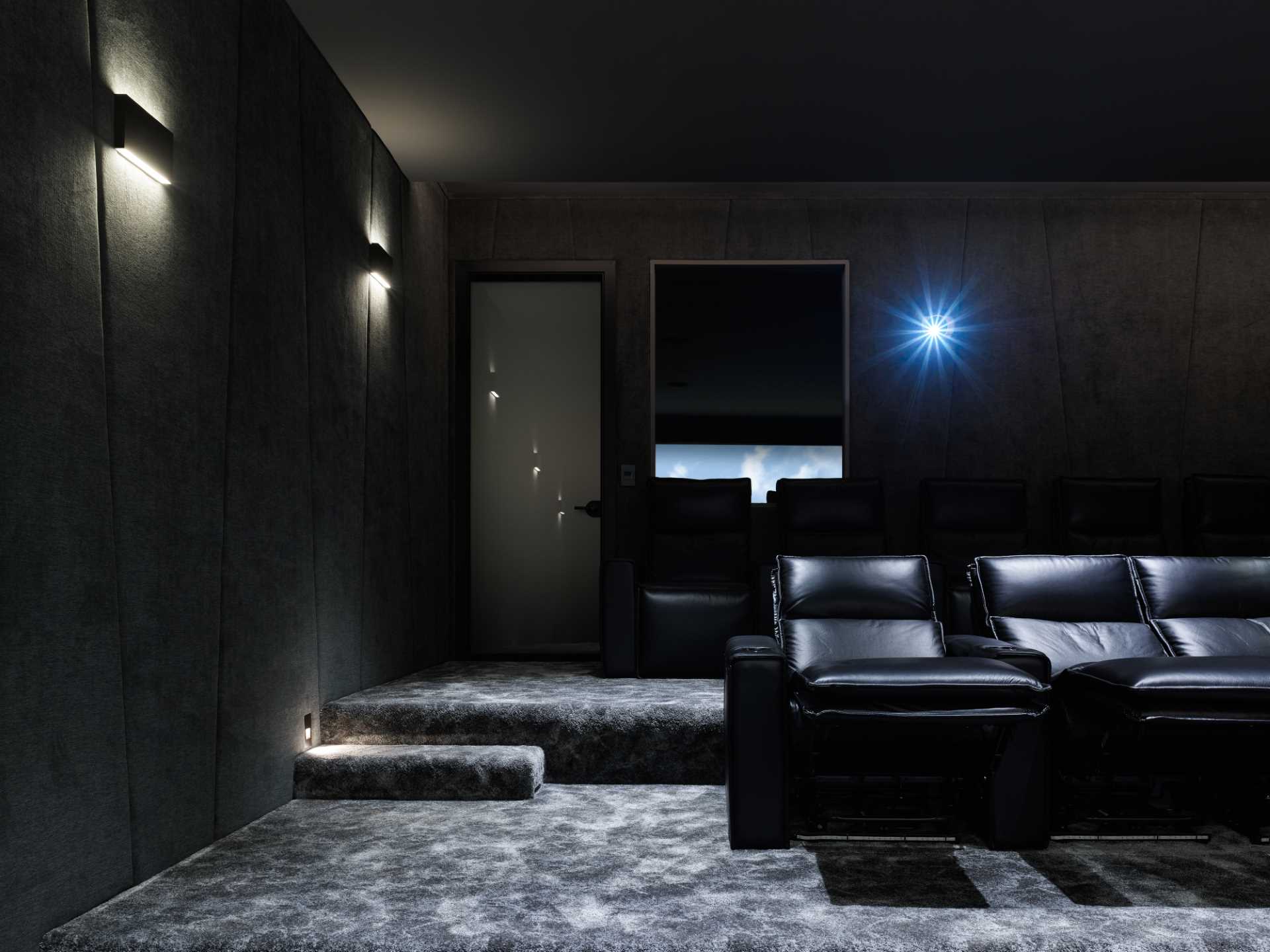 A modern media room with black walls and furniture.